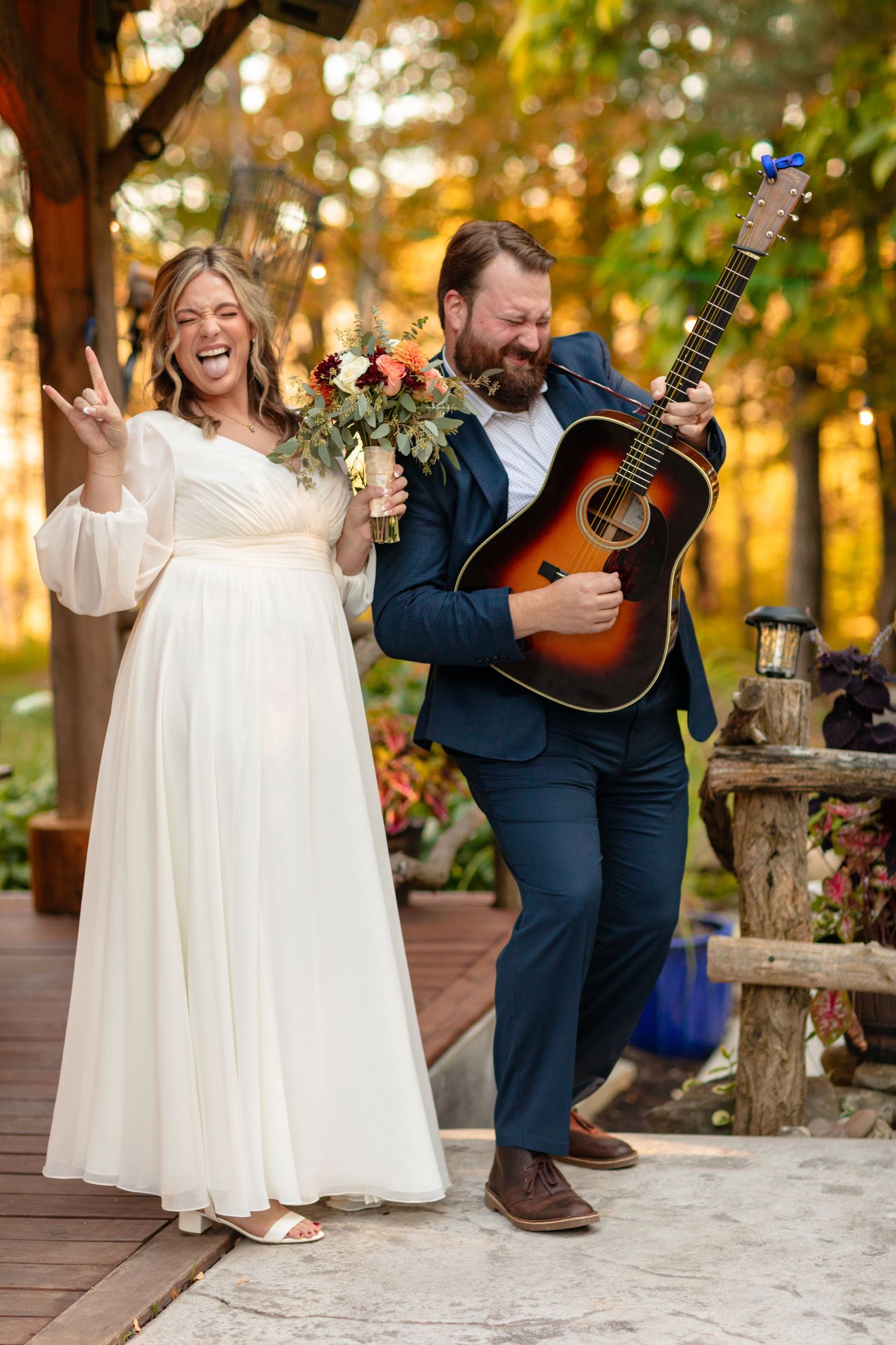Wedding couple shares intimate moments on wooden deck with acoustic guitar and autumn scenery.