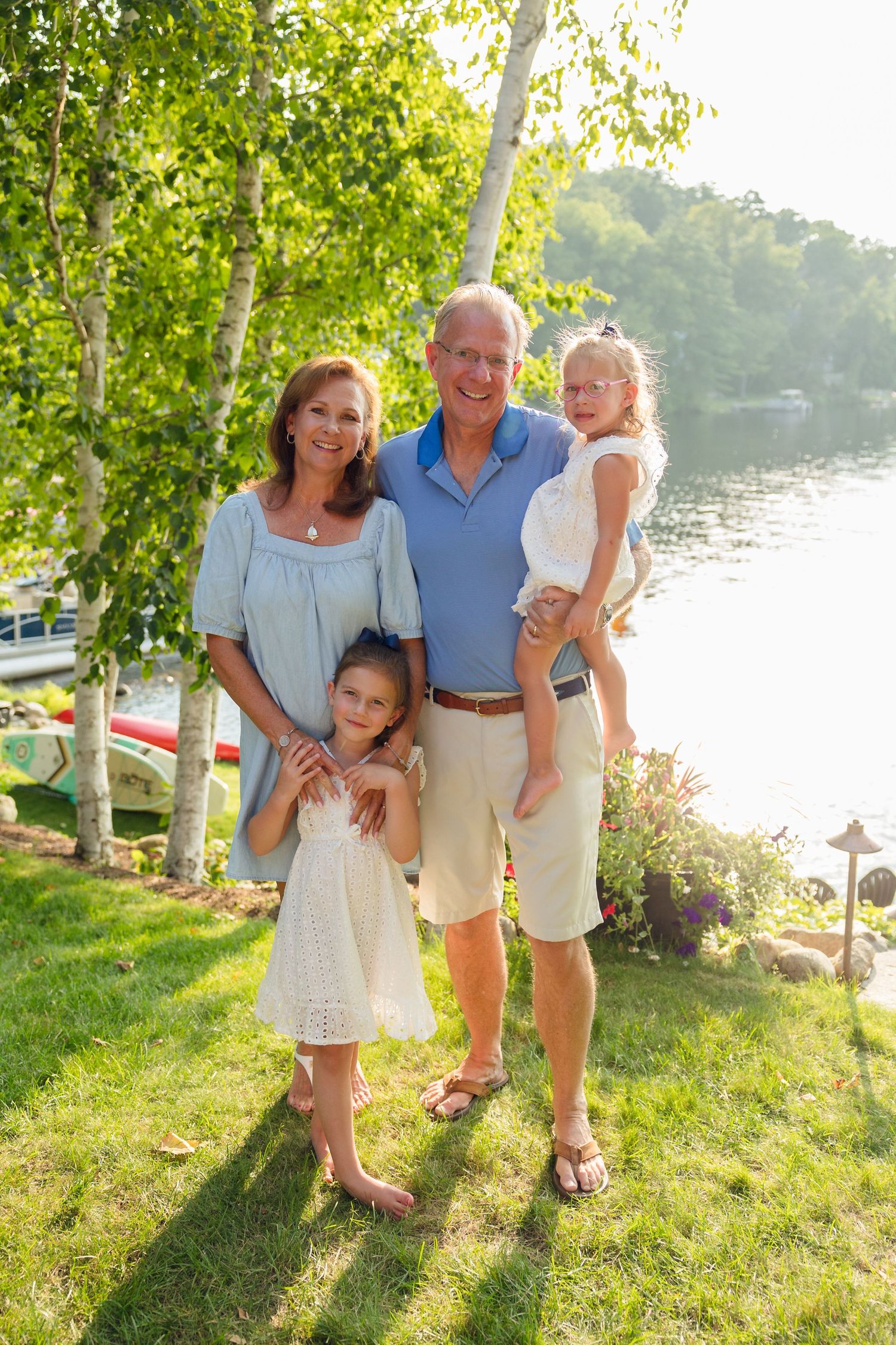 A family gathering outdoors on a sunny day by the waterfront with trees providing natural shade.