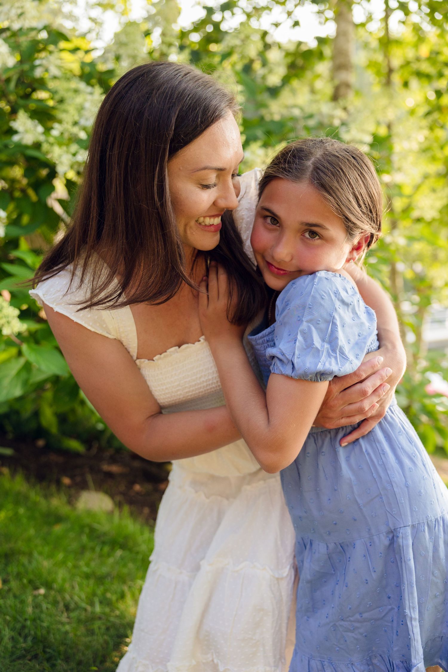 Tender moments shared between family members wearing white and blue dresses in a garden setting.