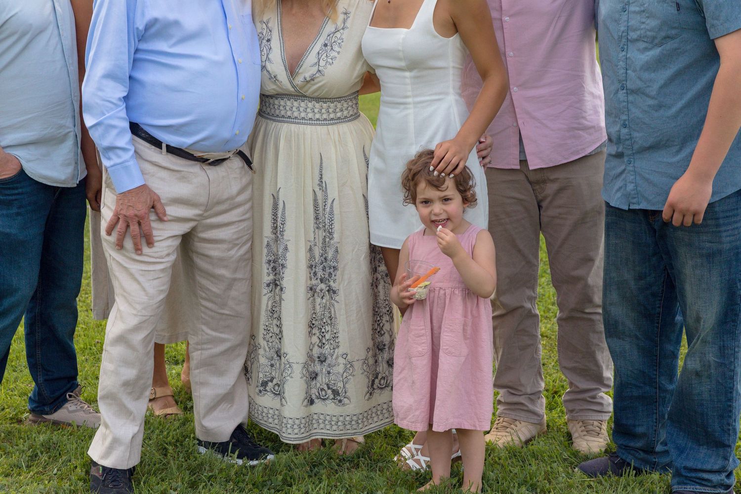 Family group photo taken outdoors showing multiple generations standing together in casual summer attire.