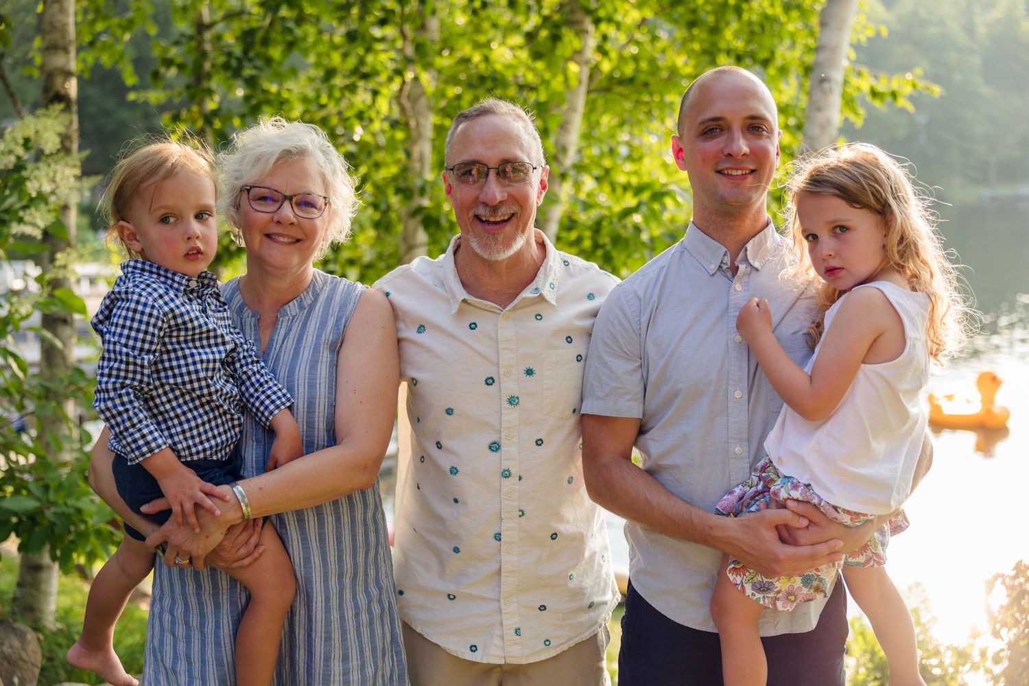 Family group photo outdoors with sunset light filtering through trees in background.