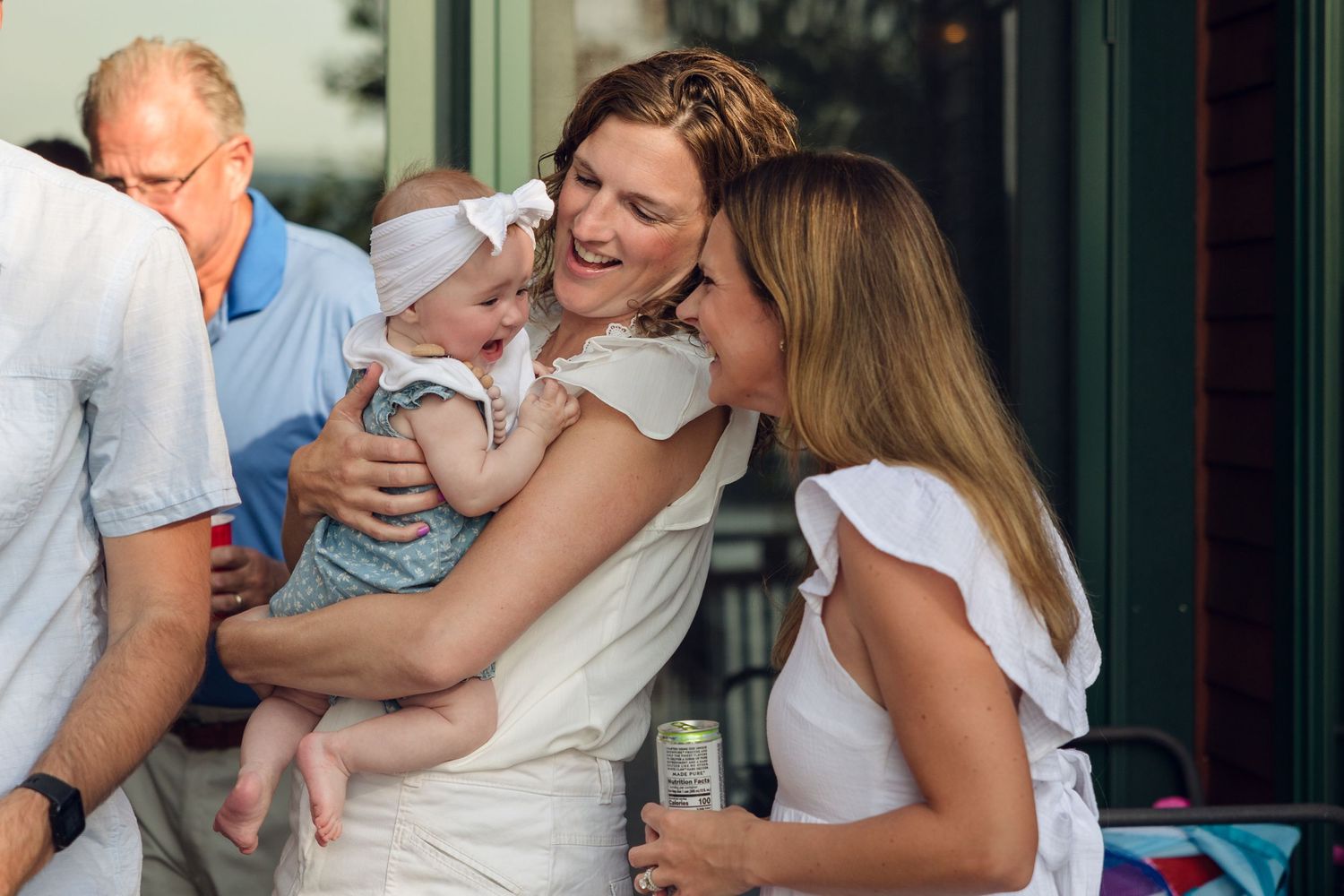 Family members sharing tender moments while holding an infant in white clothing.