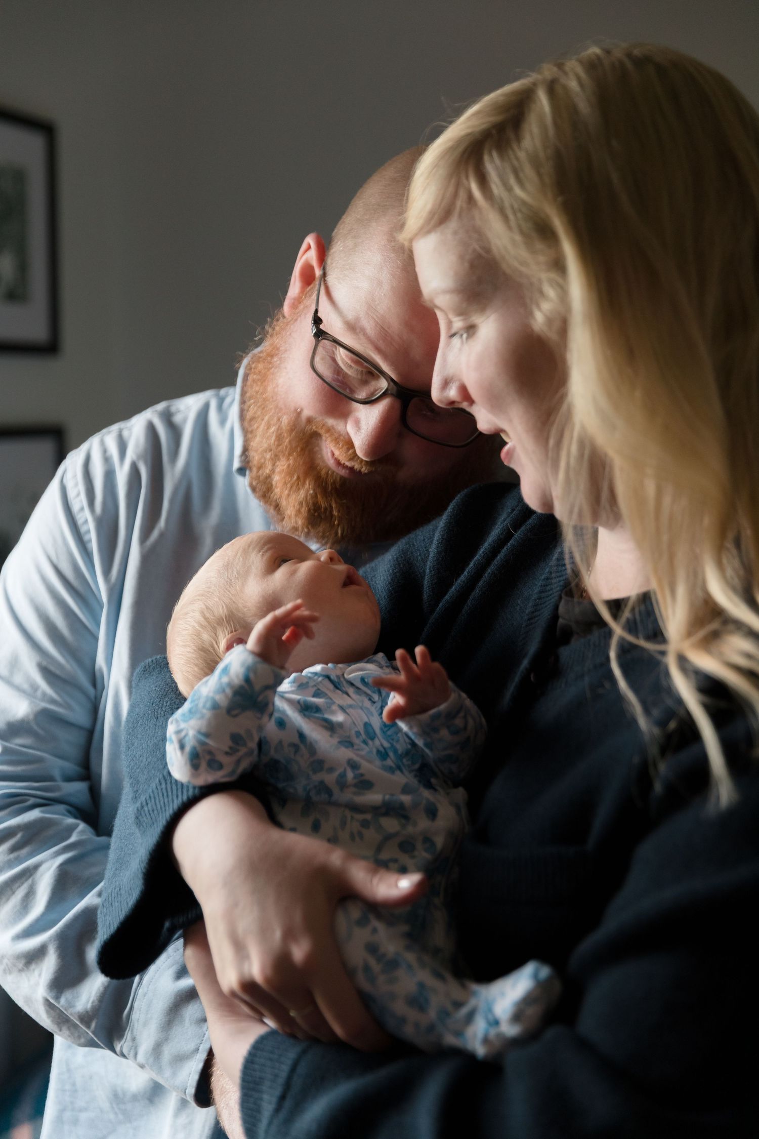 Parents cuddling with their swaddled newborn in tender embrace.