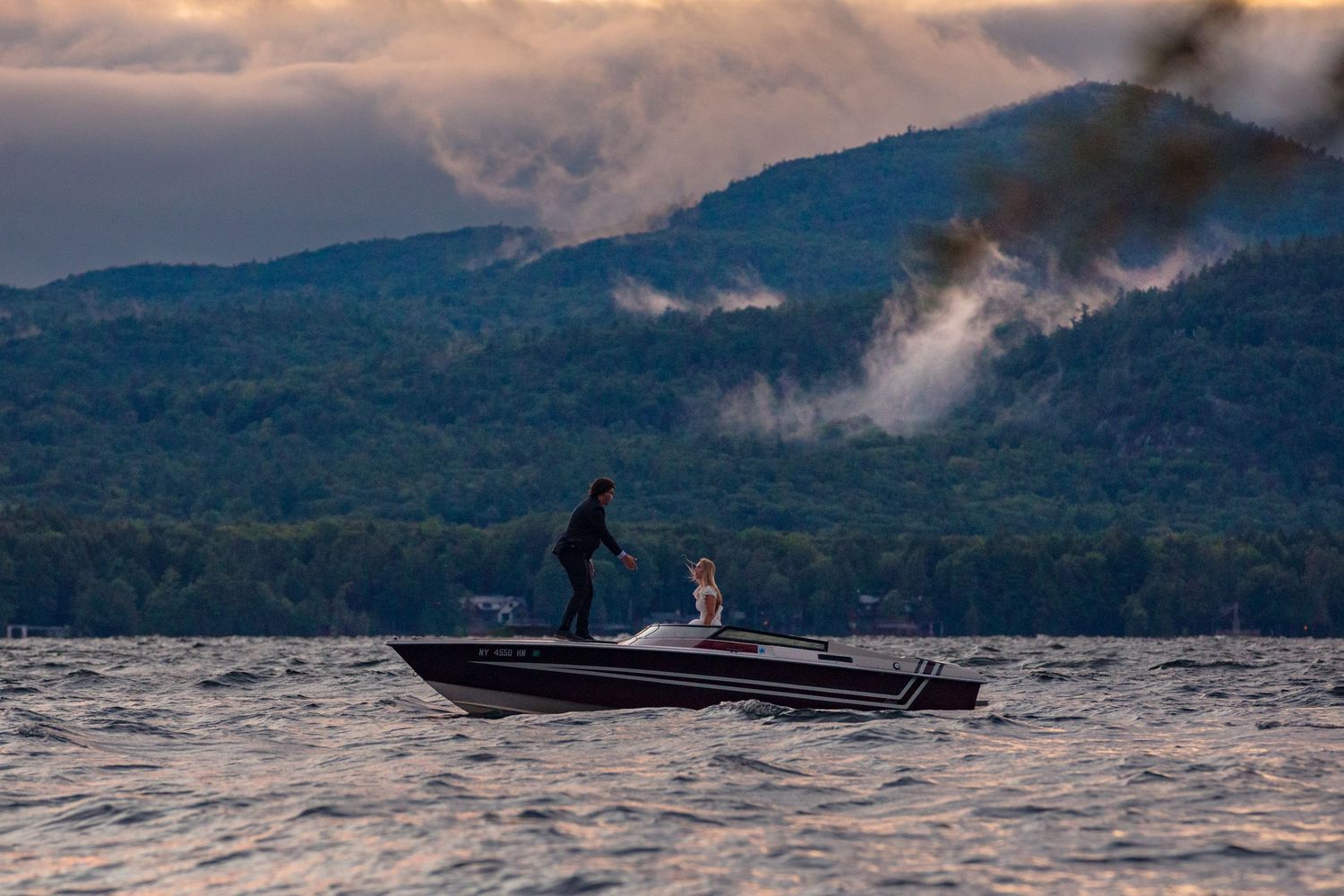 Silhouette of boat on lake against mountain landscape during golden hour.