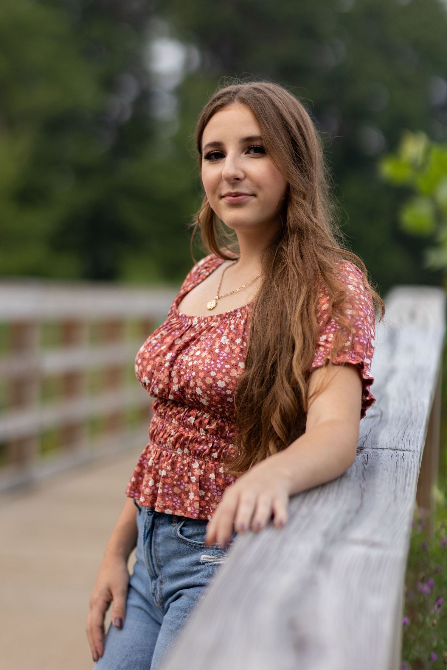Outdoor portrait series featuring floral top and denim against wooden railing.