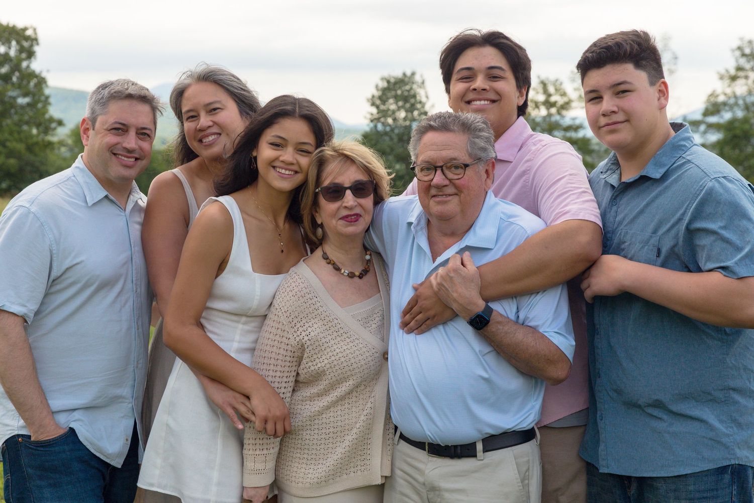 A group poses together outdoors wearing coordinated pastel and neutral colored outfits.