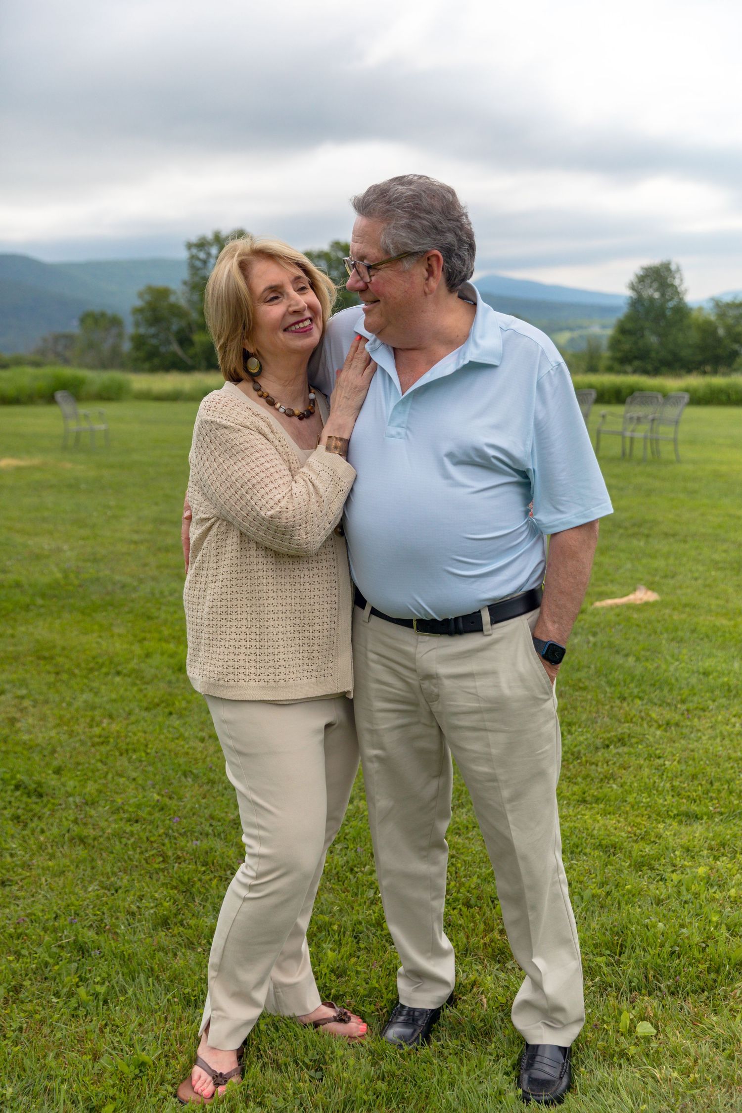 A couple shares a tender moment while standing together in a green field.