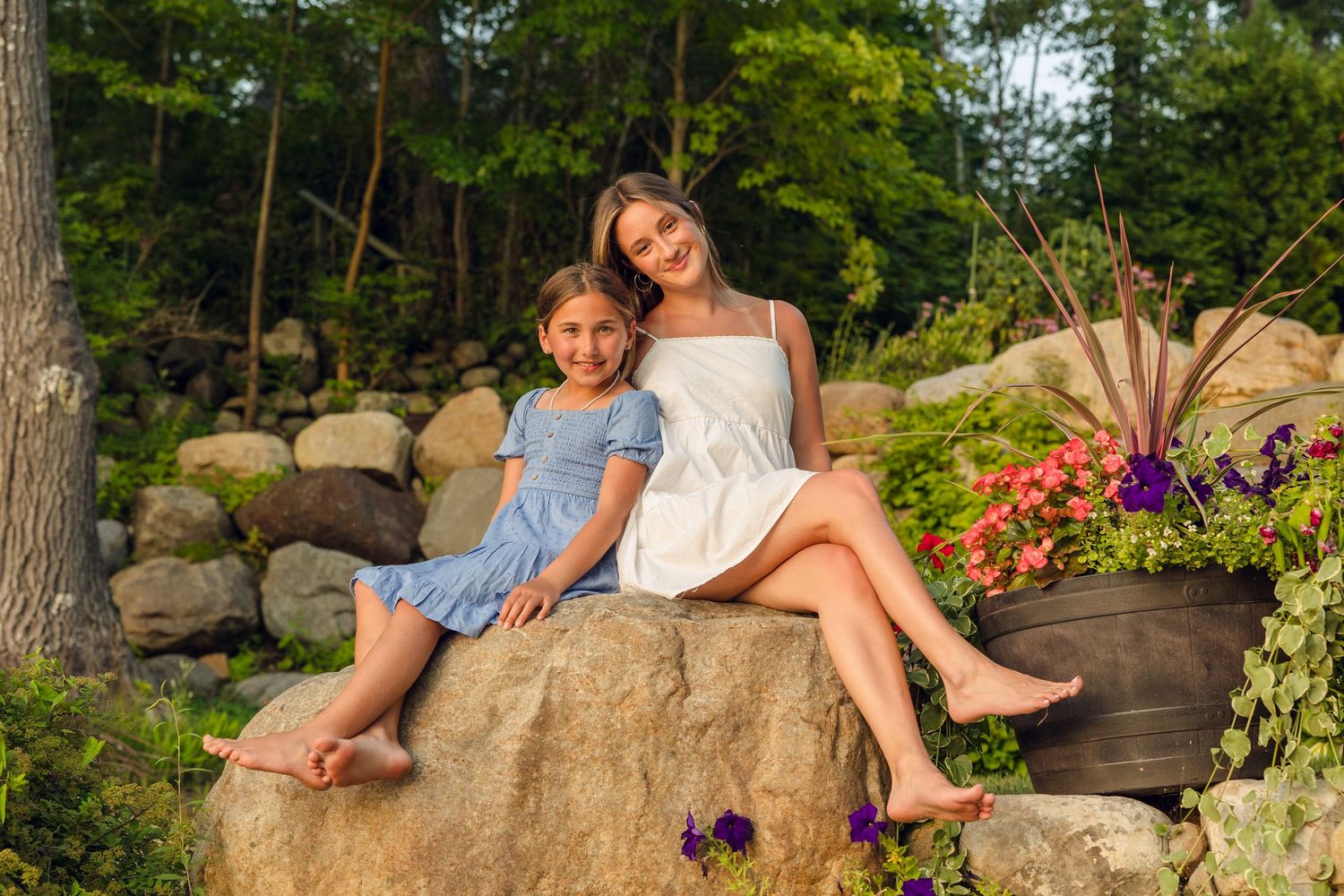People sitting together on large rock formation in garden setting at sunset.