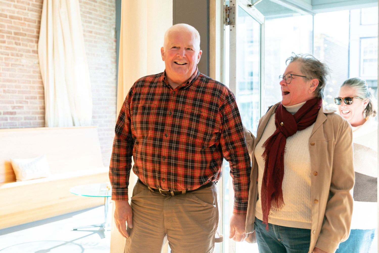 People interacting and laughing in a bright room with brick walls and large windows.