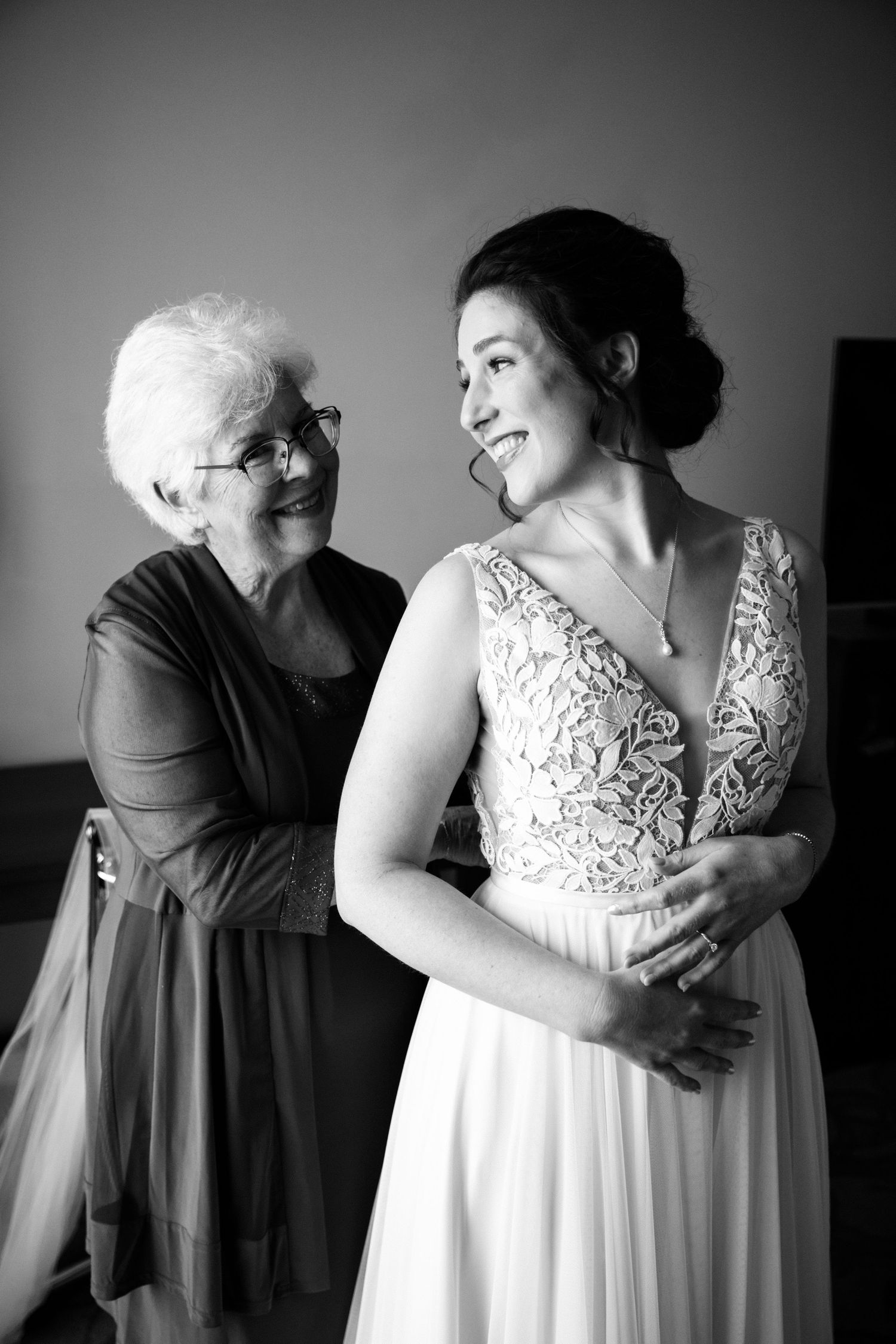 Black and white candid moments of wedding dress preparation with emotional embraces.