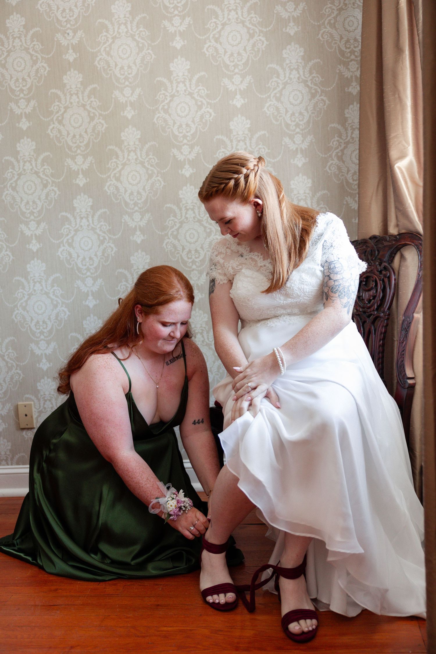 The Brides lovely little sister helps her on with her wedding shoes.