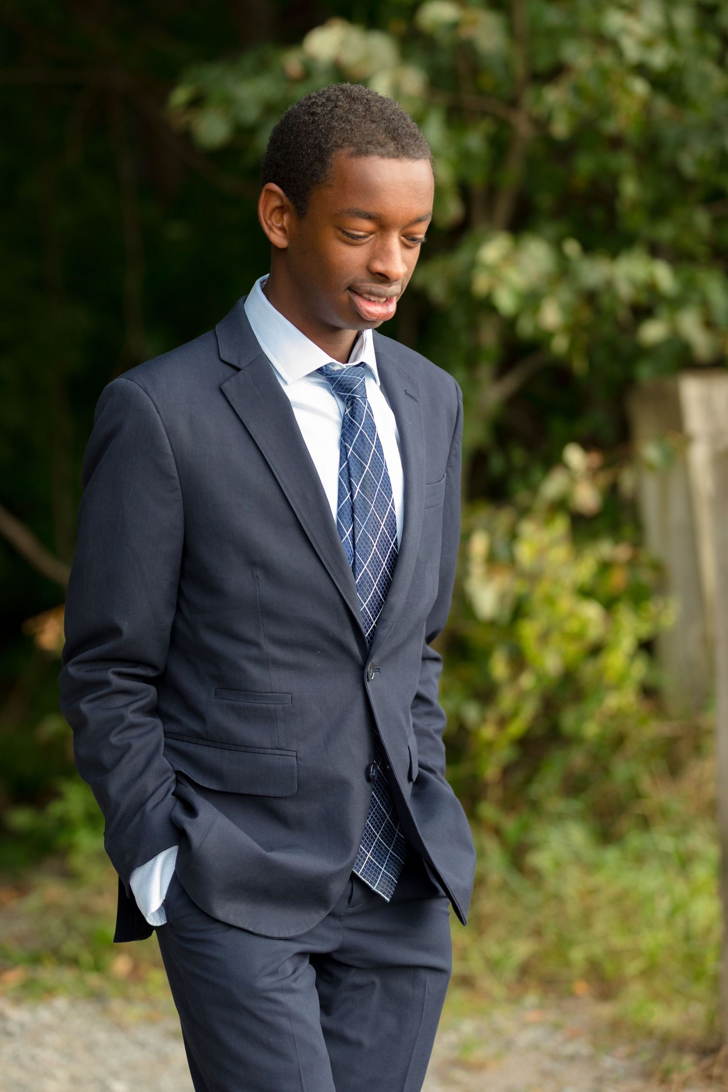A person in a dark suit strikes casual poses during an outdoor photo session.