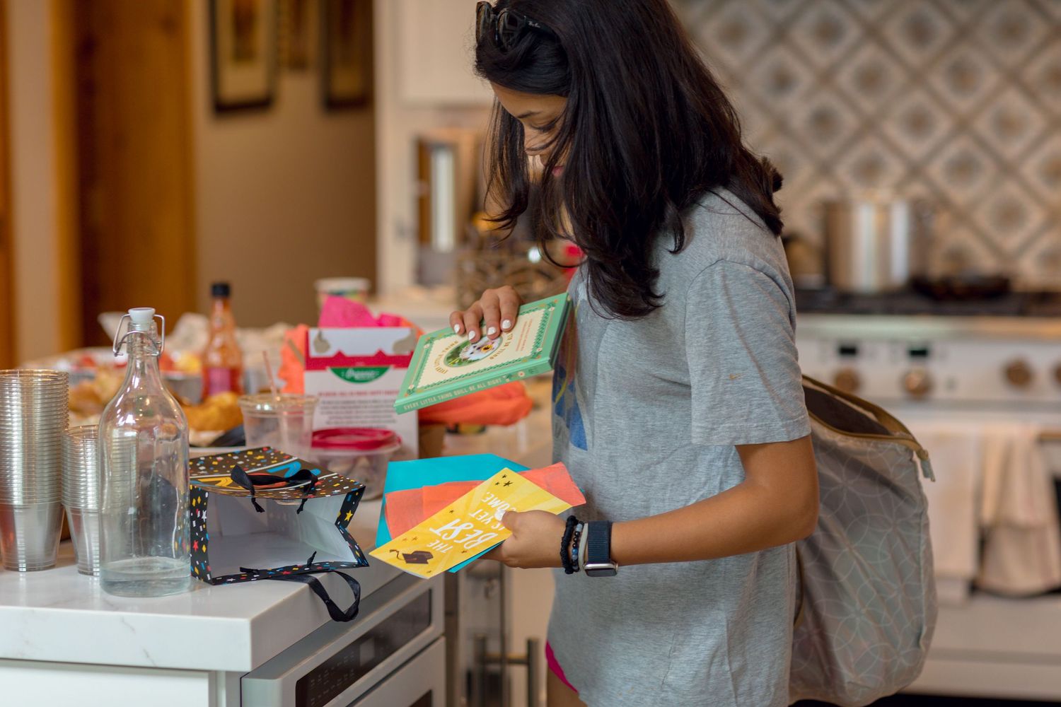 People preparing food and cooking in a modern white kitchen with patterned backsplash.