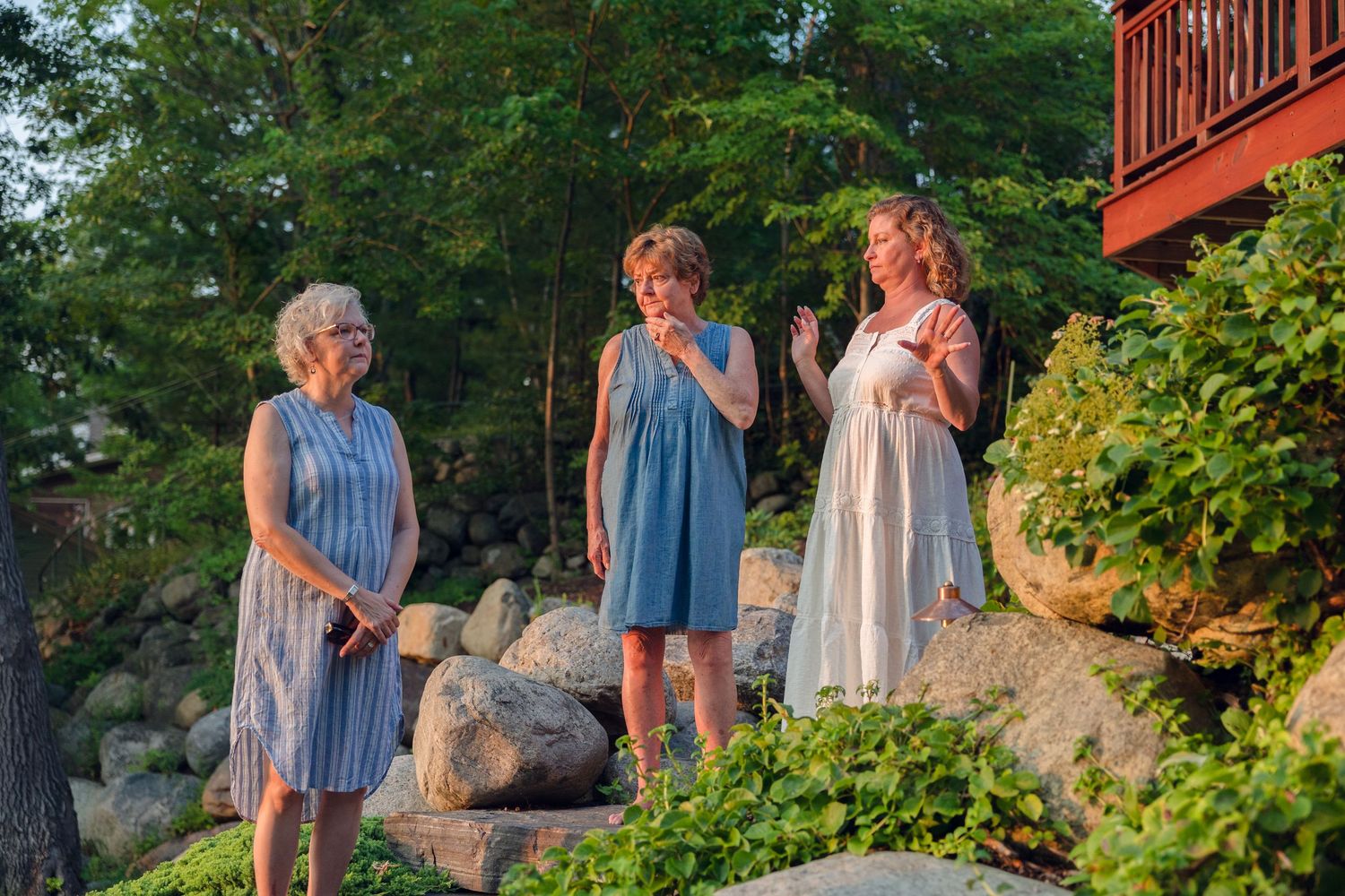 People gathered on a deck during golden hour with trees in the background.