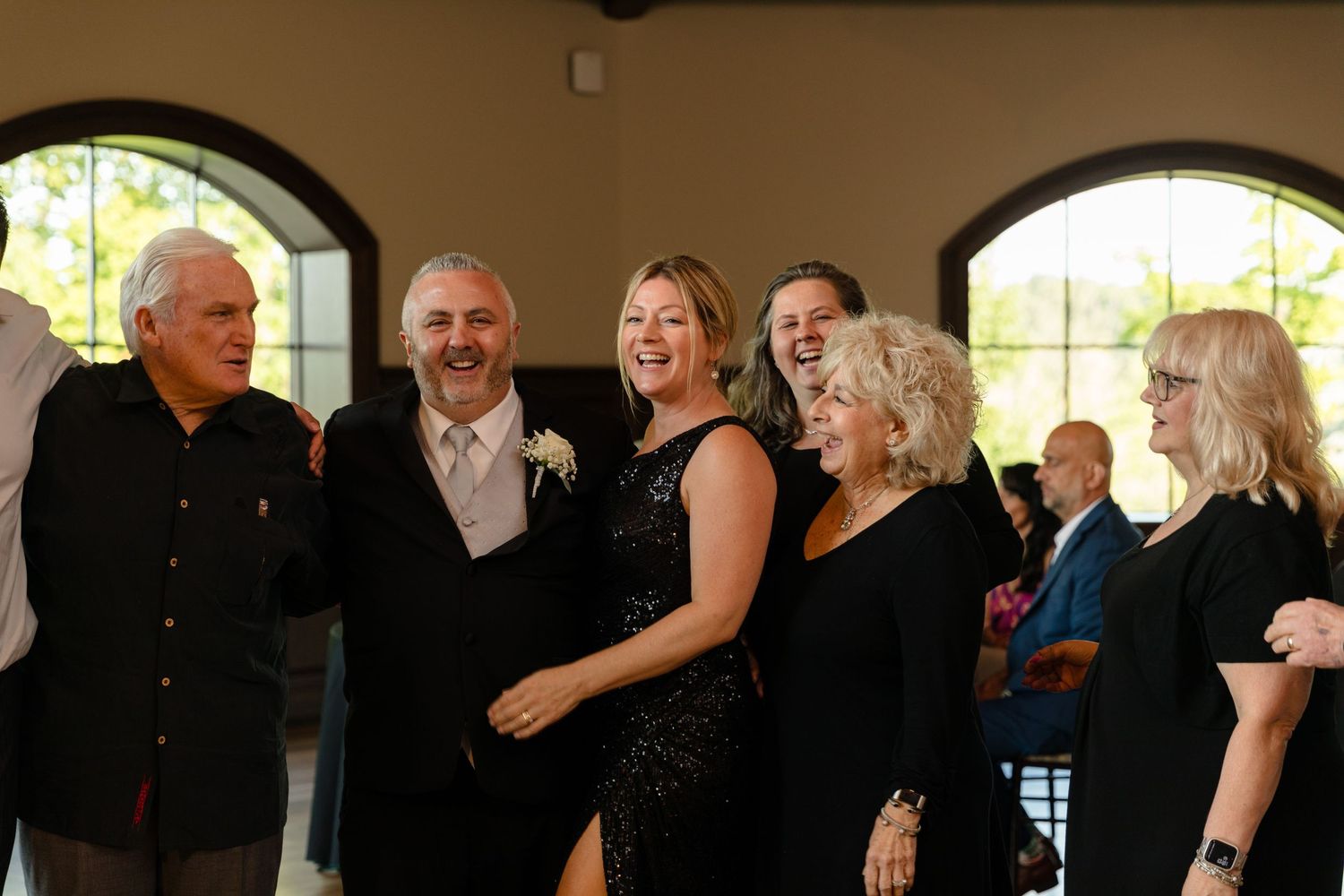 Guests in formal black attire gathered at an elegant indoor event.