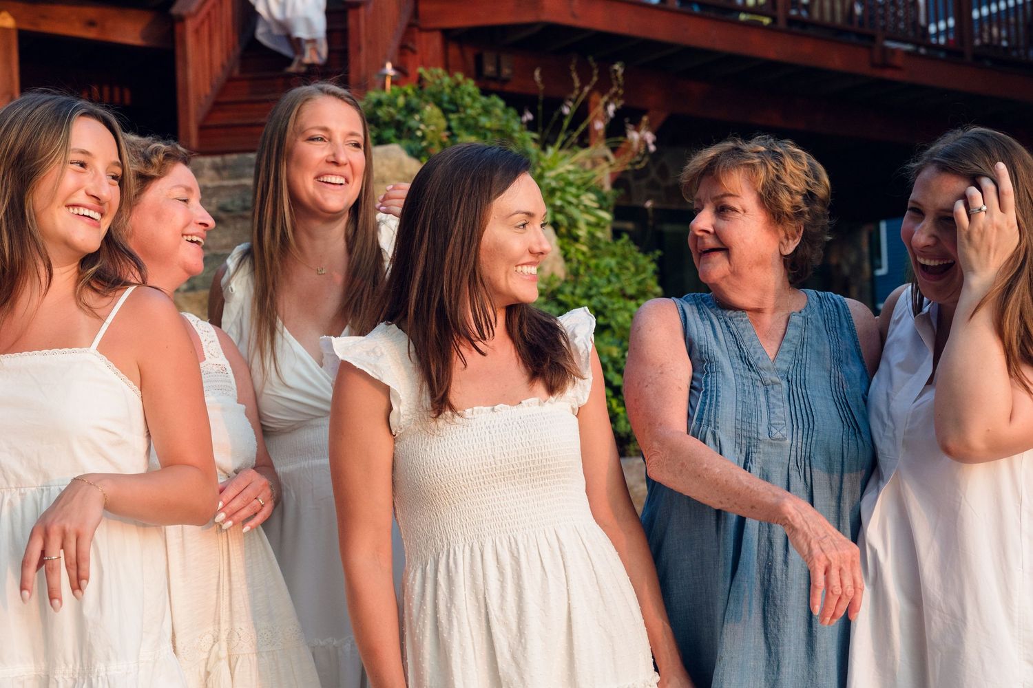 Friends in matching white and blue dresses standing together on a summer evening.