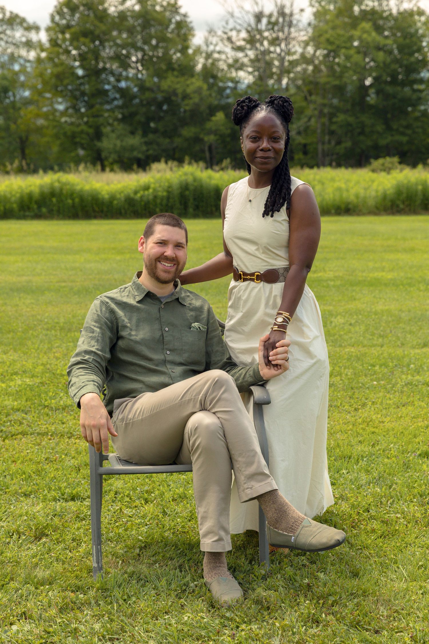 Couple sitting together on a bench in a scenic outdoor field setting.