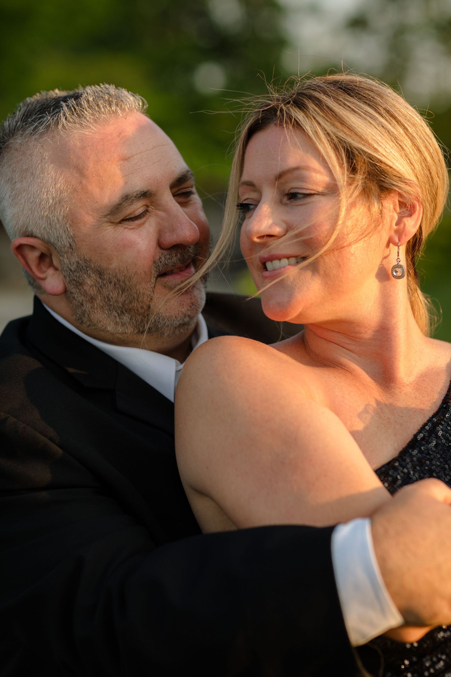 A romantic couple embraces in warm sunset lighting during an outdoor photo session.