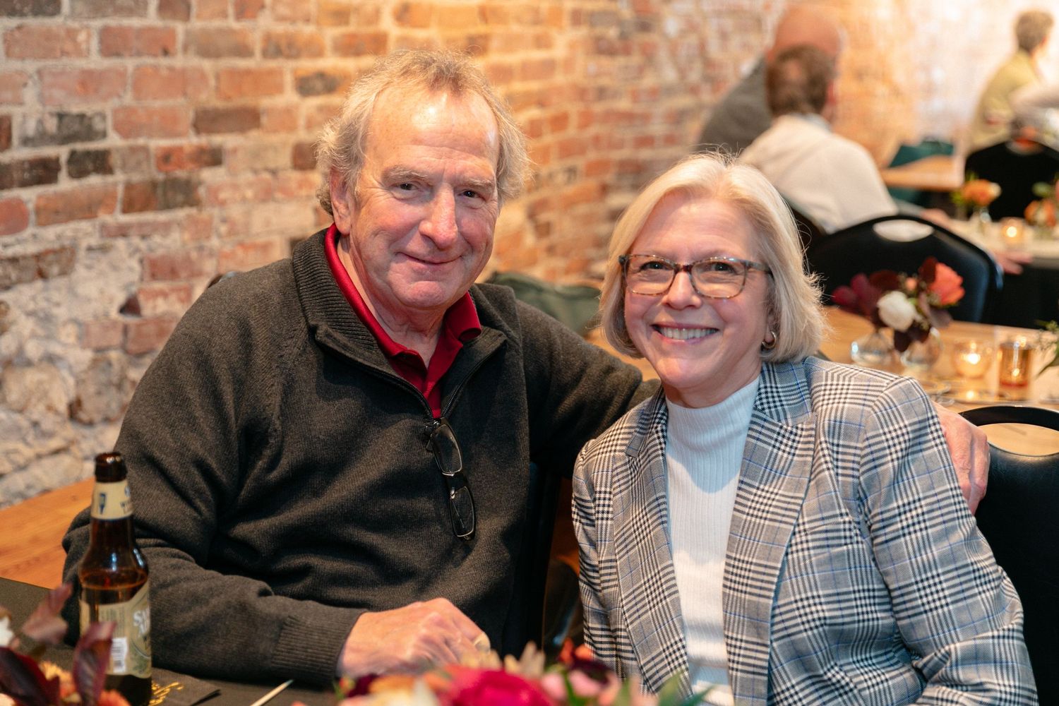 Group enjoying conversation at a casual gathering with brick wall backdrop.