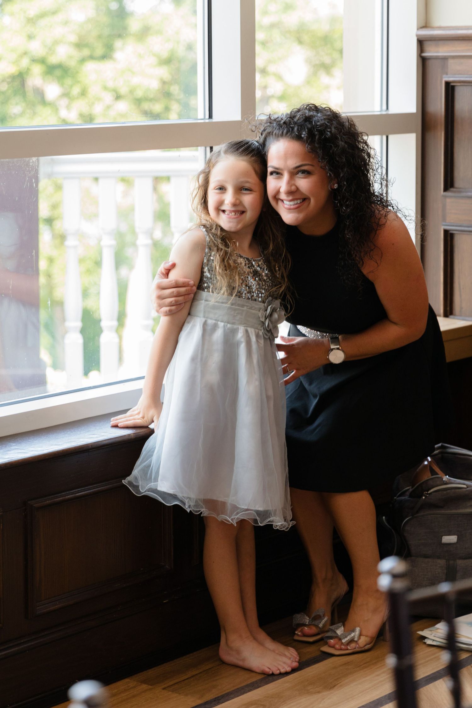 Two people share a tender moment near large windows in an indoor venue.