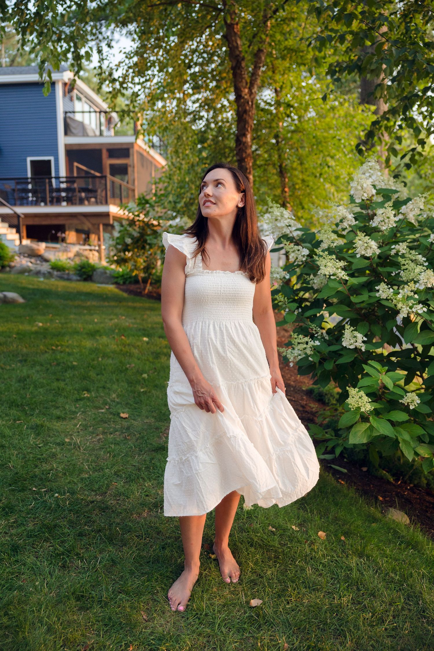 A playful scene of someone dancing in a white dress on a grassy lawn.