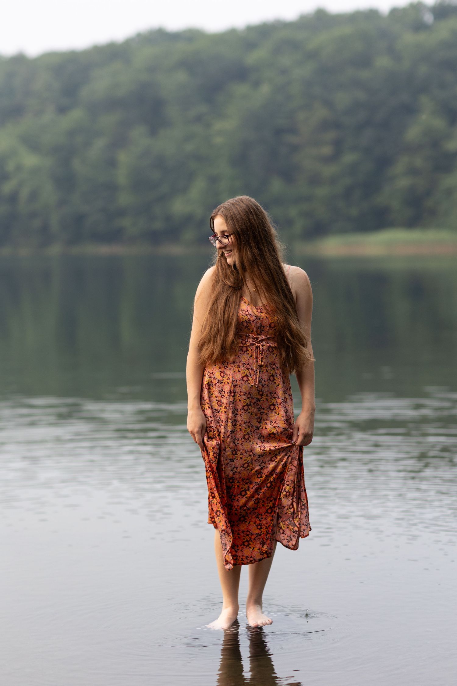 A floral dress creates a dreamy silhouette while standing in calm lake waters.