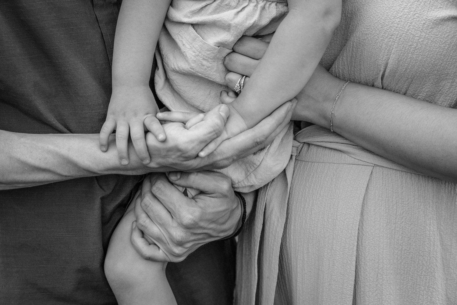 Close-up black and white detail shots of hands holding each other in formal attire.