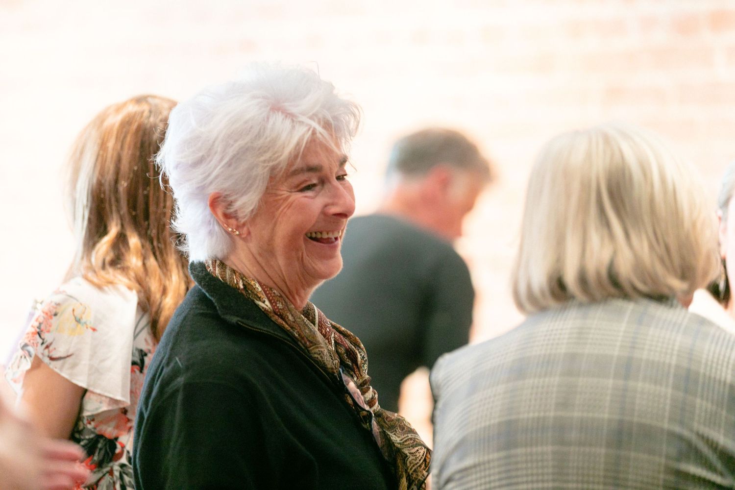 Guests mingling at a celebration event with brick wall background.