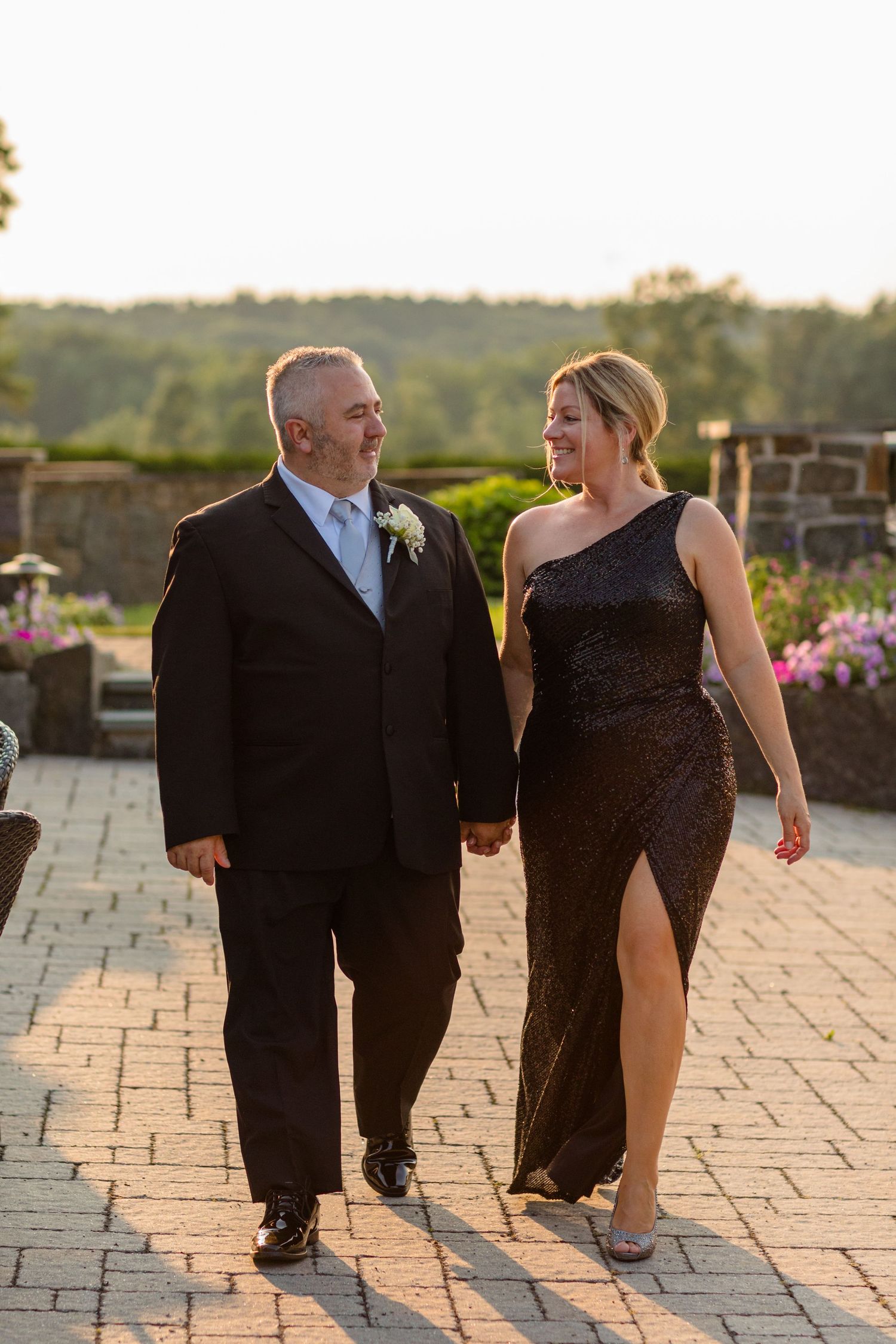 A couple walking together on a stone patio during sunset.