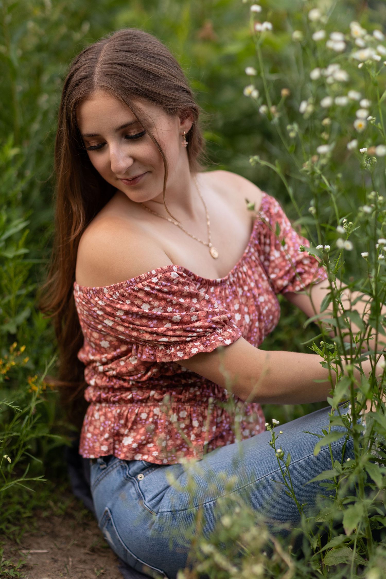 Candid outdoor portraits among wildflowers wearing floral top and jeans.