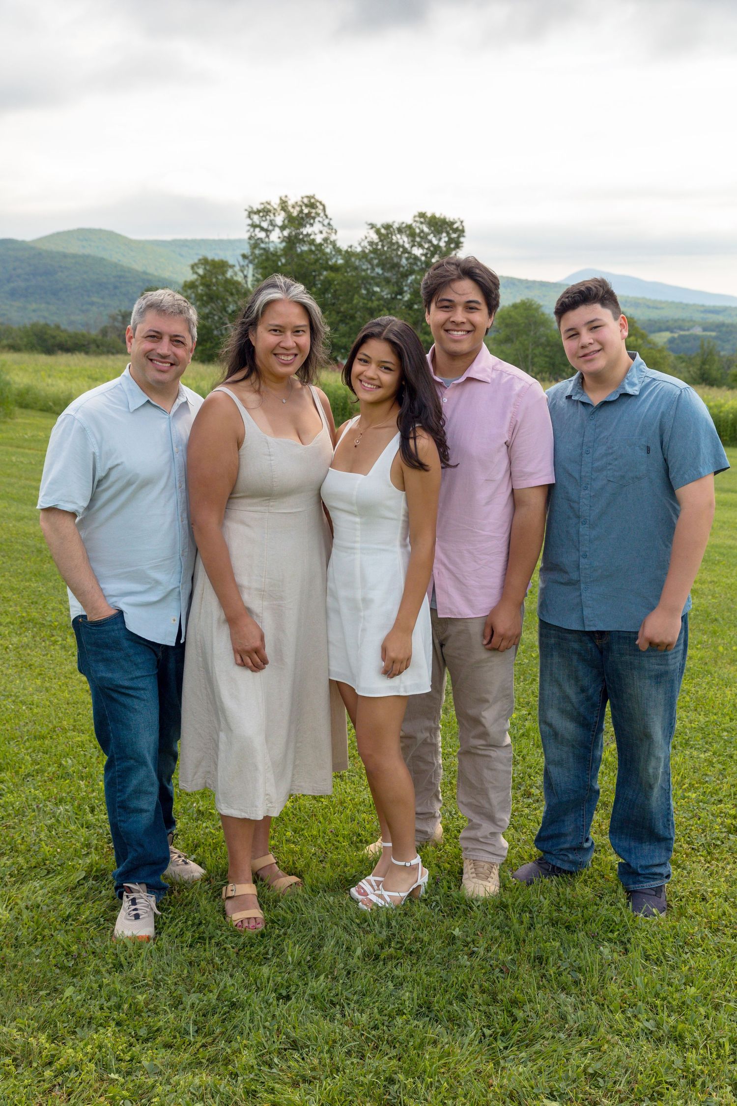 Group portrait of family members lined up on grass with mountains visible in the distance.