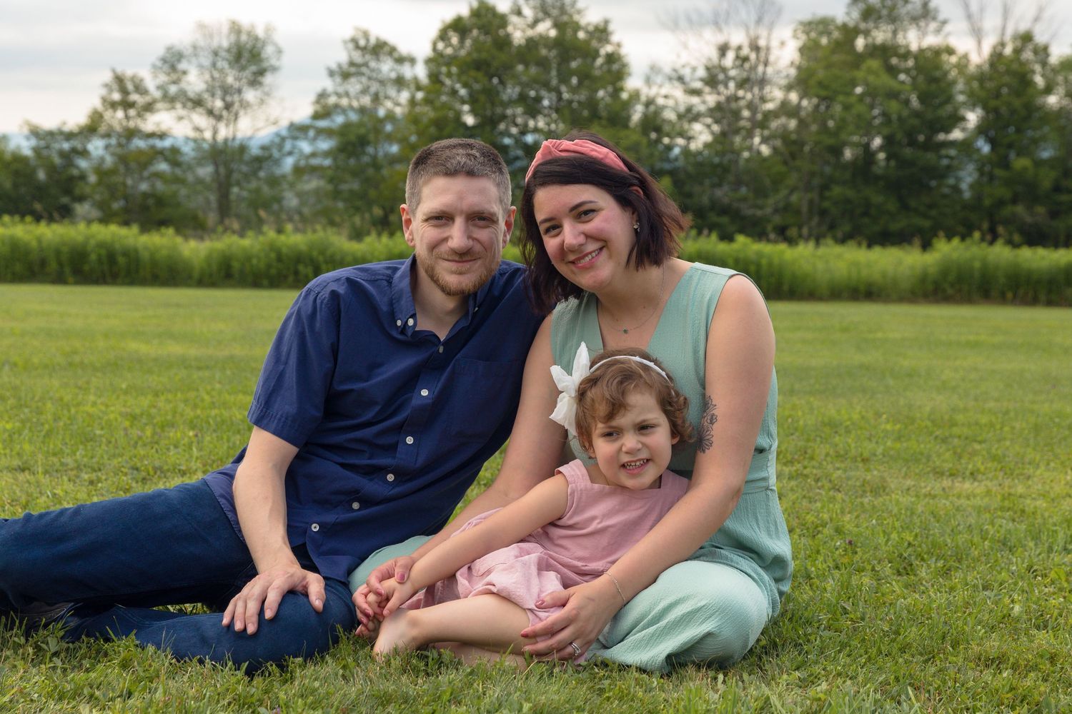 Family lying together on green grass during an outdoor photo session.
