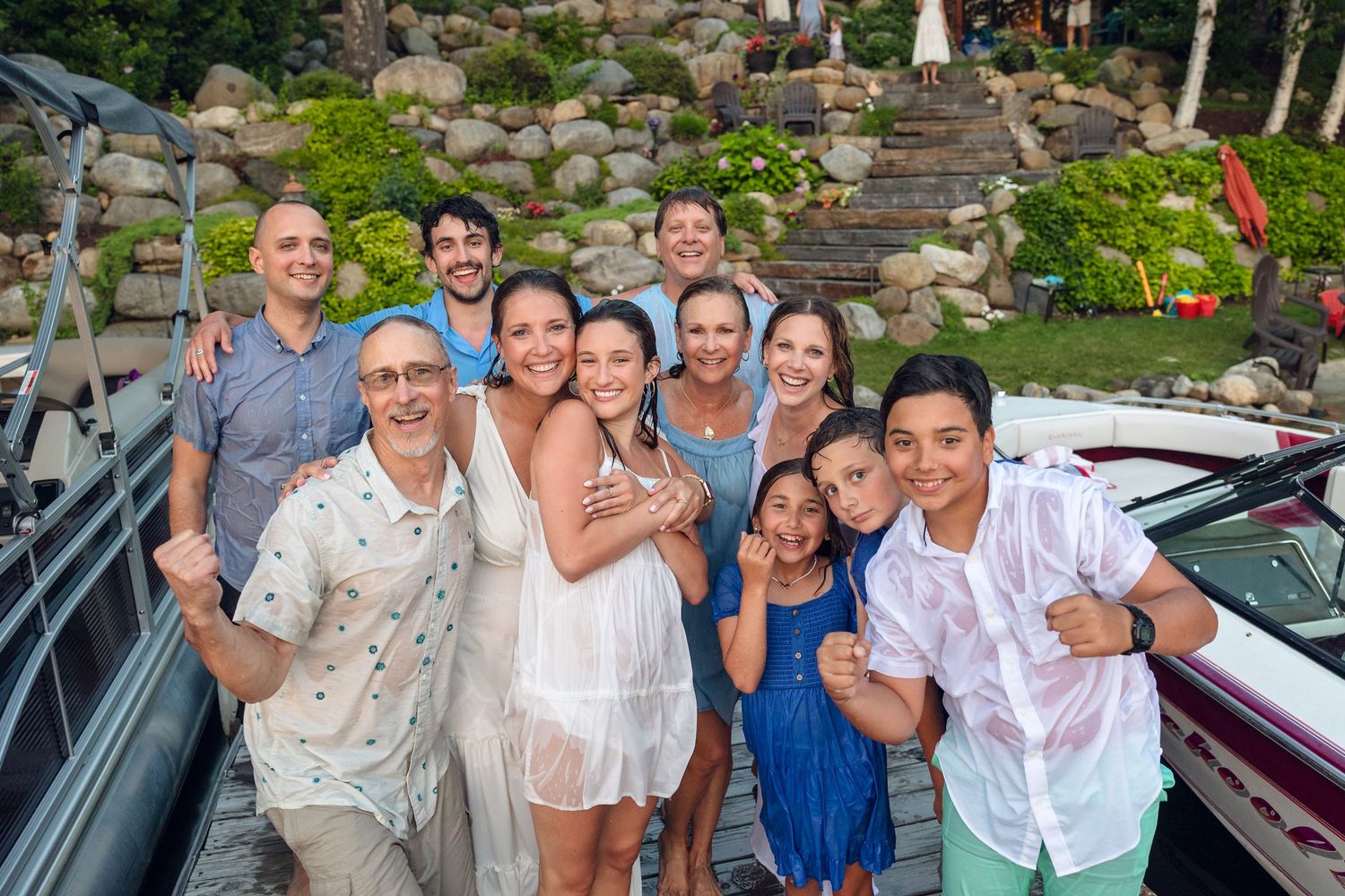 Candid group photo of party guests celebrating outdoors near a lakeside venue.