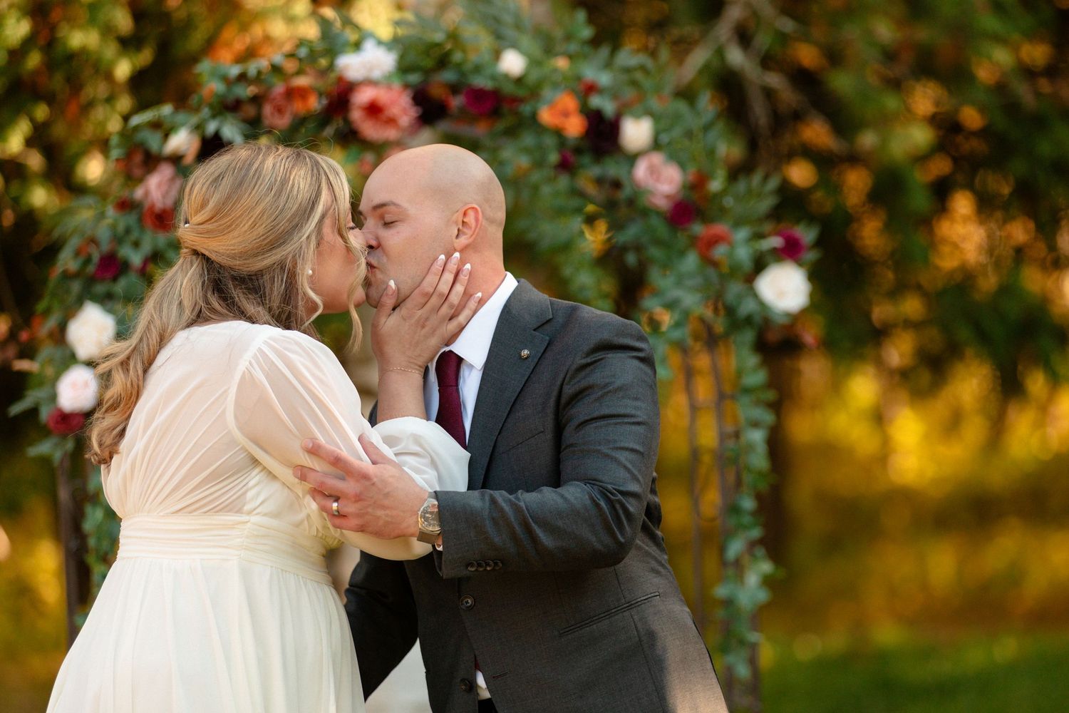 Romantic autumn wedding portraits with golden sunlight filtering through trees.