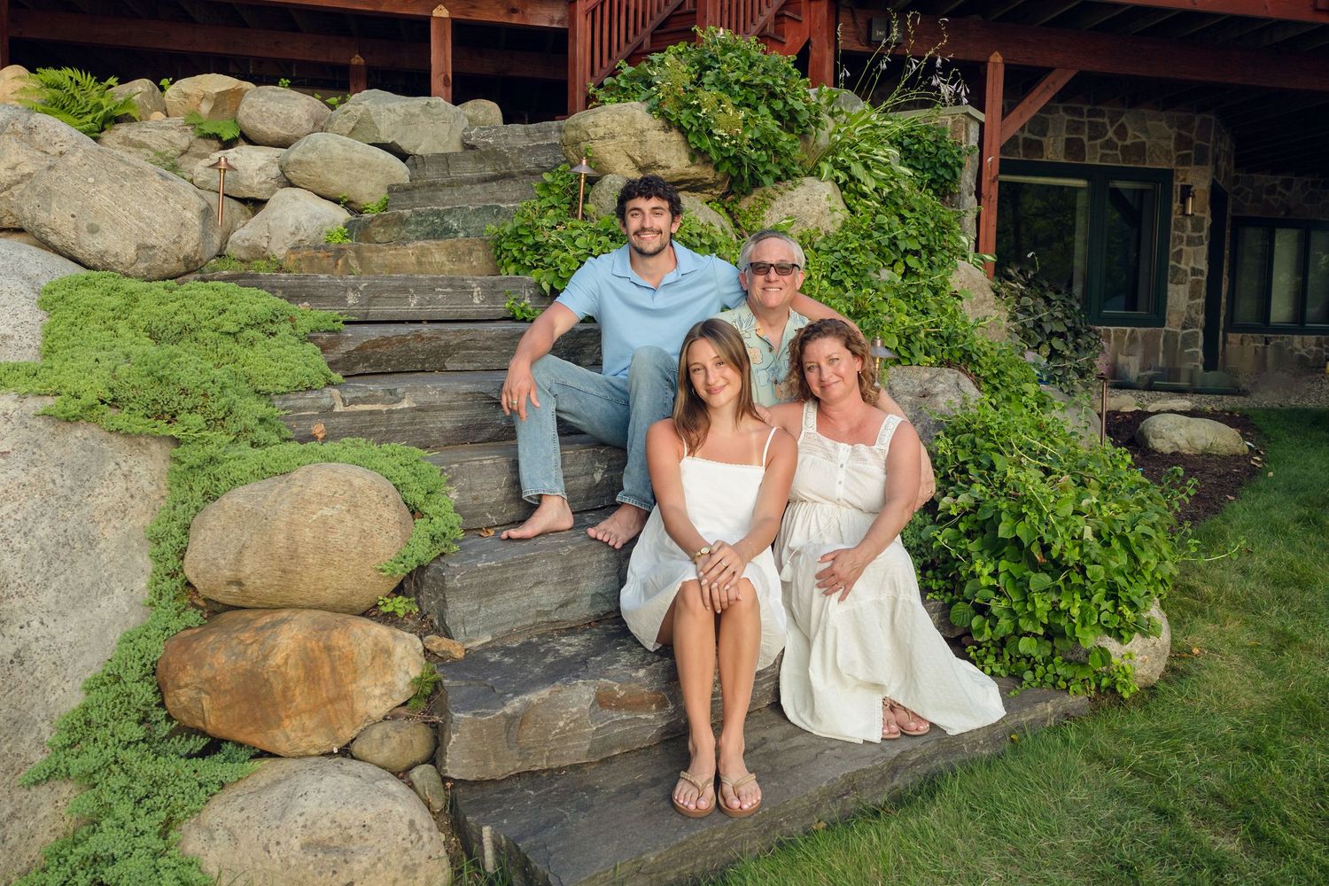 Family members sitting casually on large rocks in a garden setting.