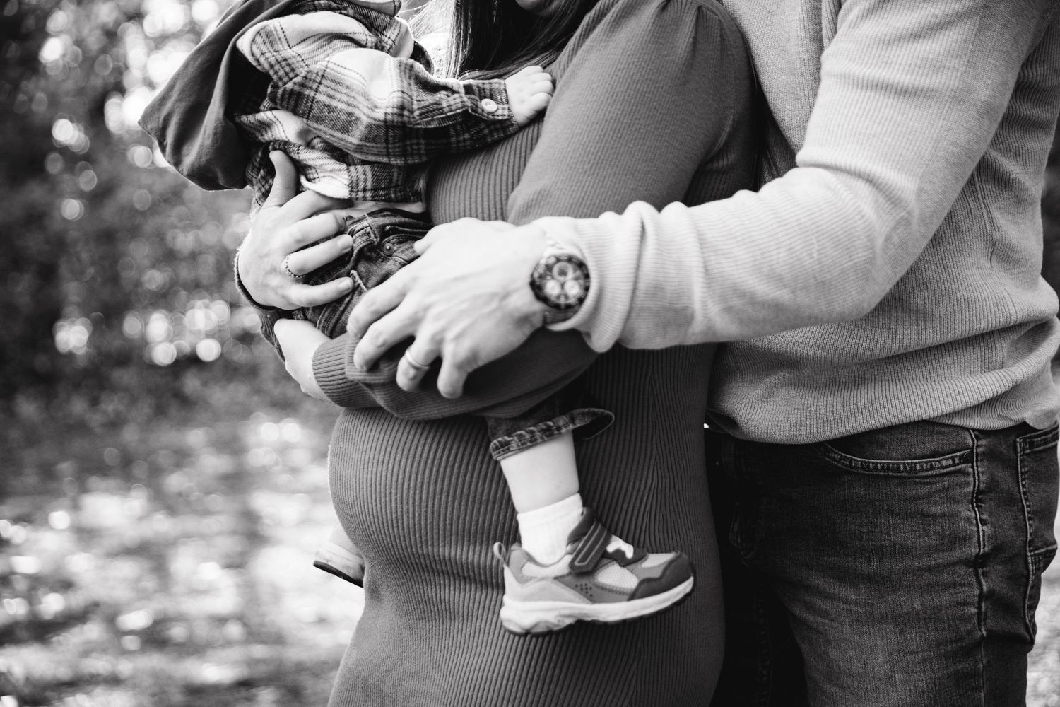 Close-up shots of hands holding ultrasound images during a pregnancy announcement photo session.