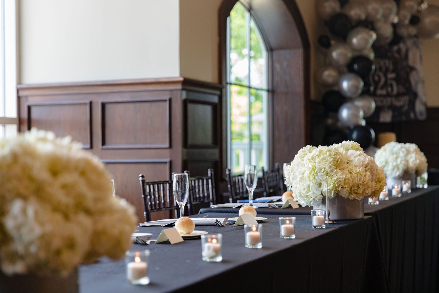 White floral centerpieces and candles decorate tables at an elegant reception.