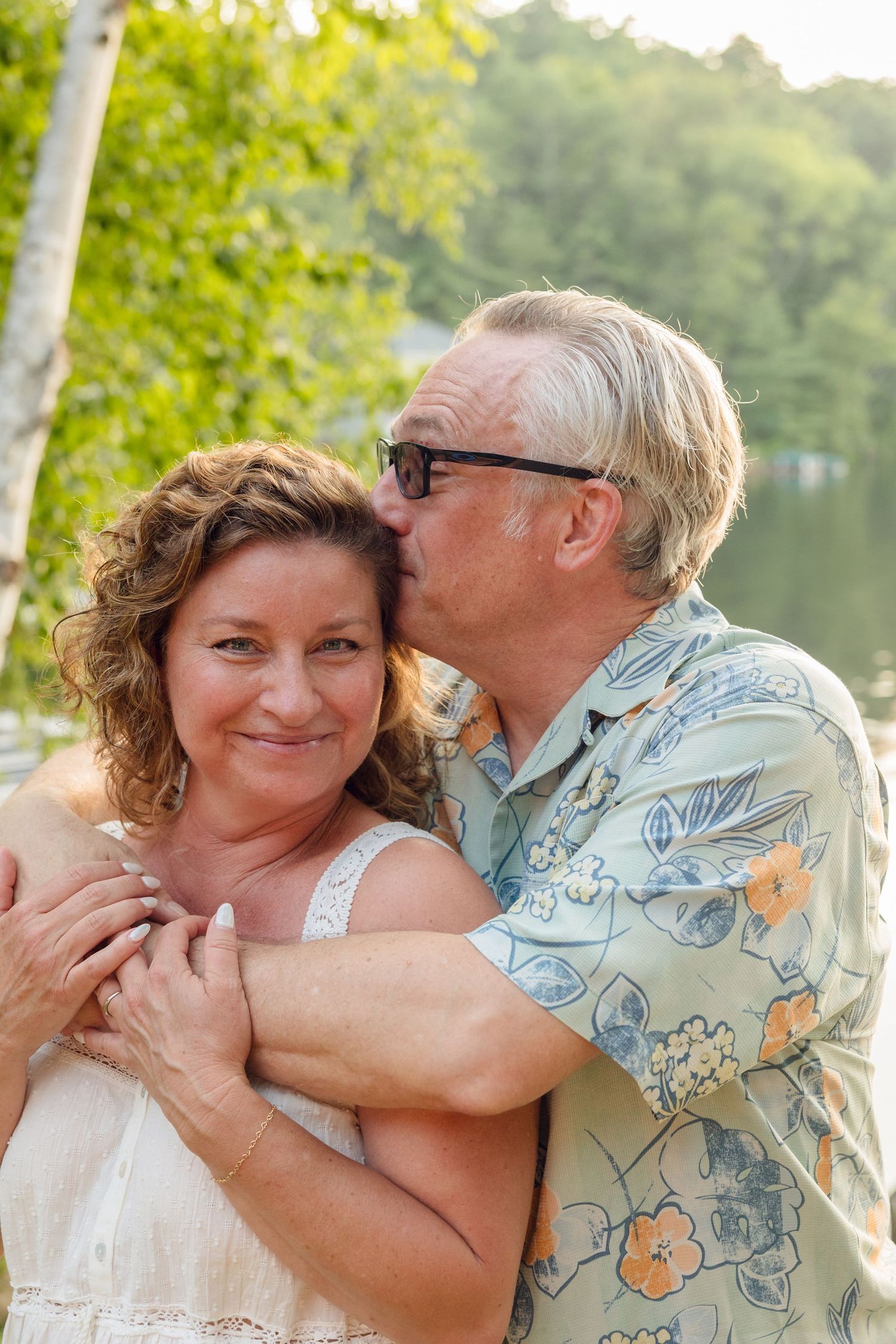 Affectionate couple sharing tender moments outdoors with trees in background.