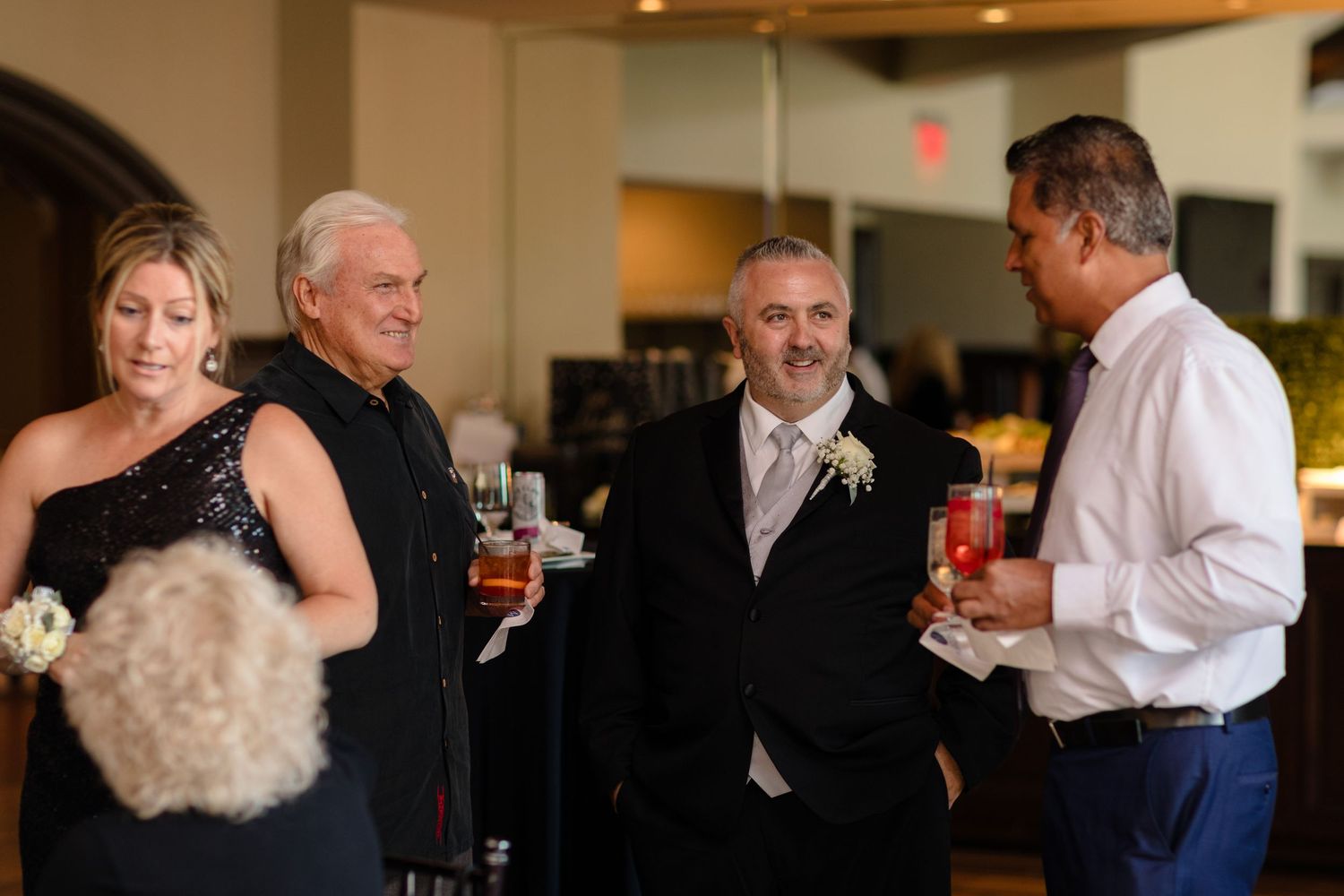 People mingling and socializing at an indoor reception with natural lighting.