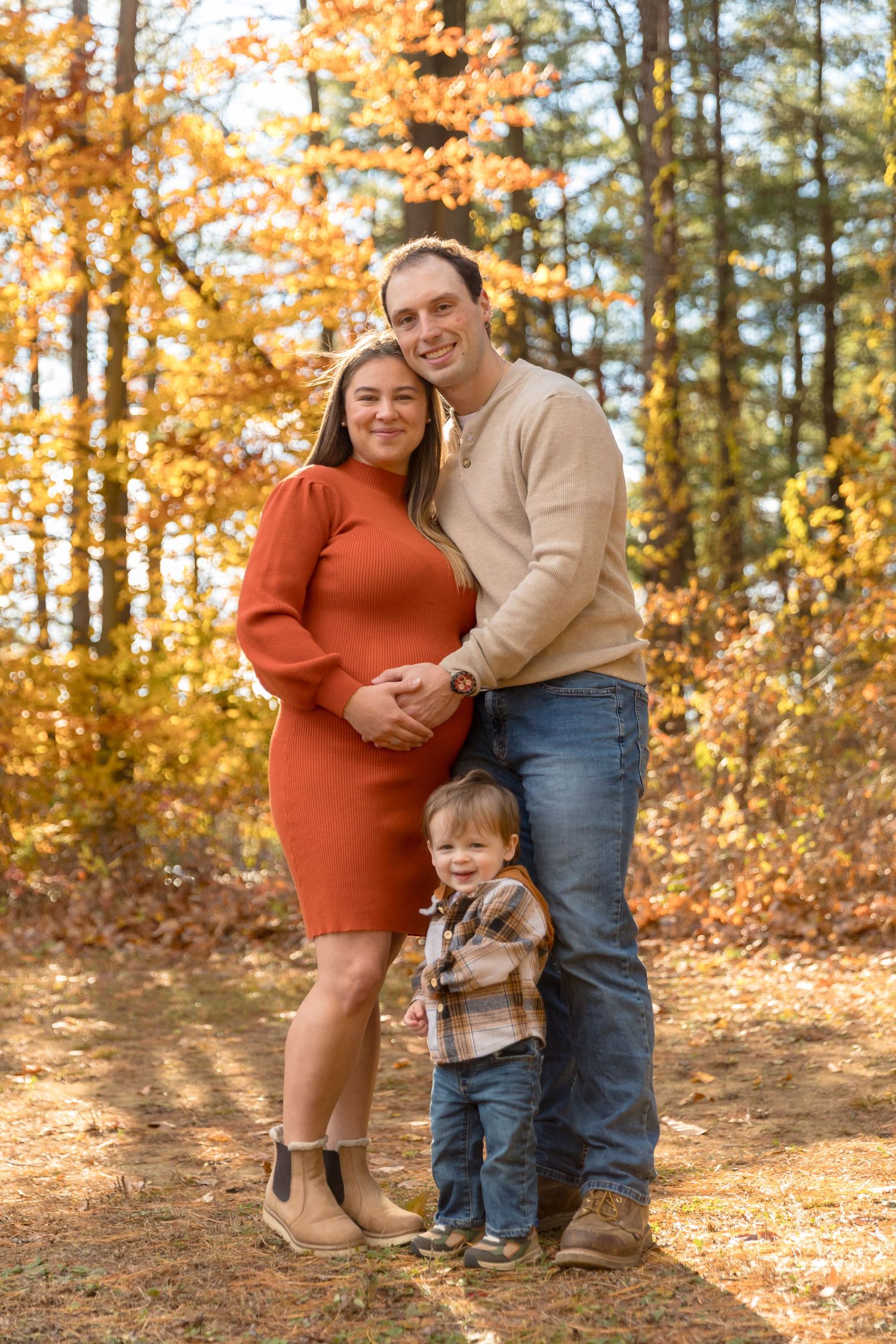Family poses together among fall foliage during an autumn photo session.