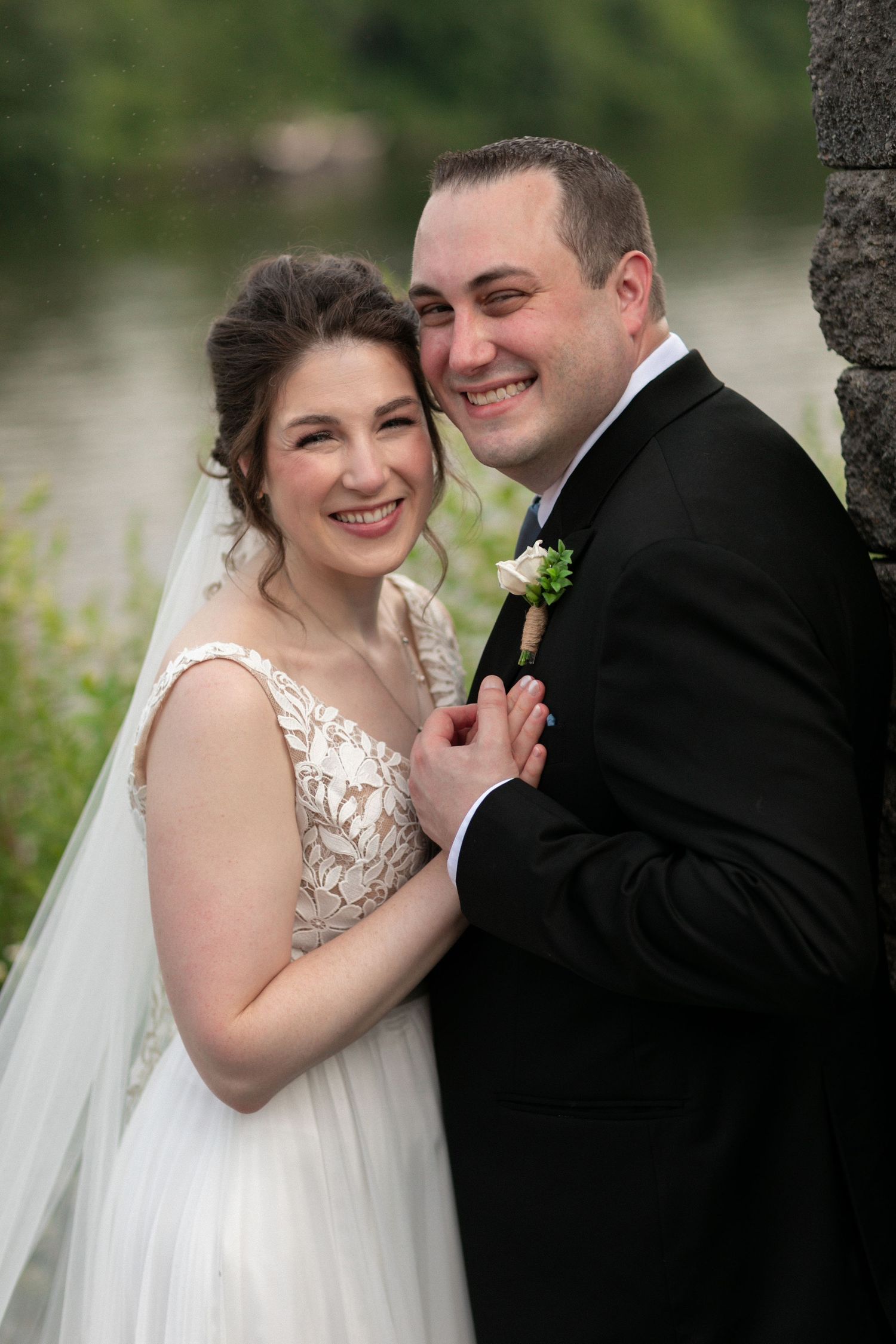 A joyful wedding portrait outdoors with a natural backdrop.