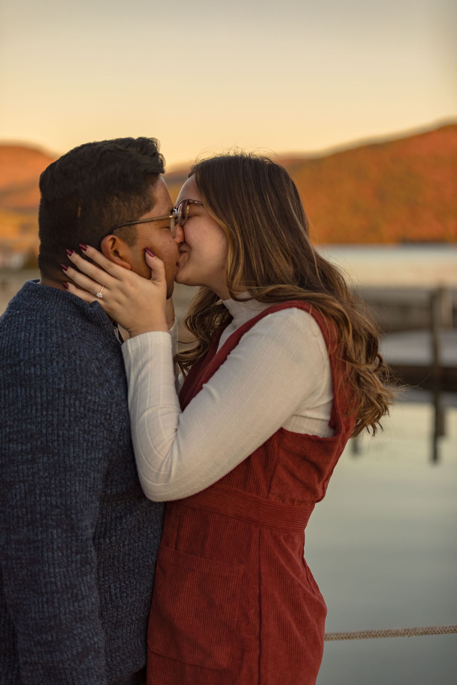 Romantic couple sharing intimate moment at sunset by waterfront.