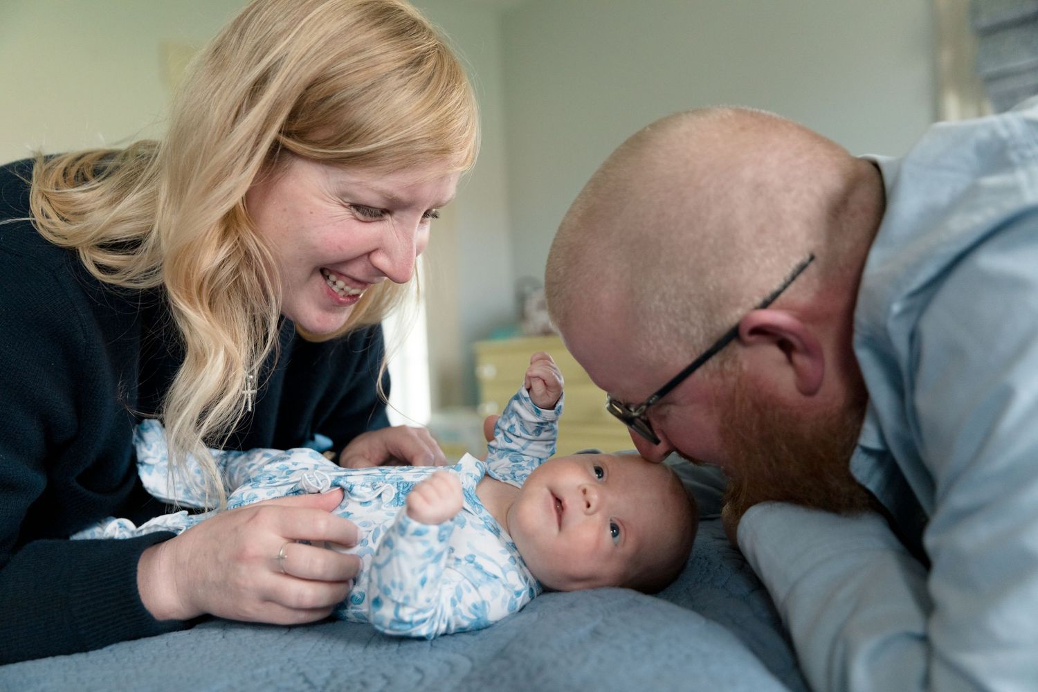 Parents sharing an intimate moment with their newborn baby on a couch.