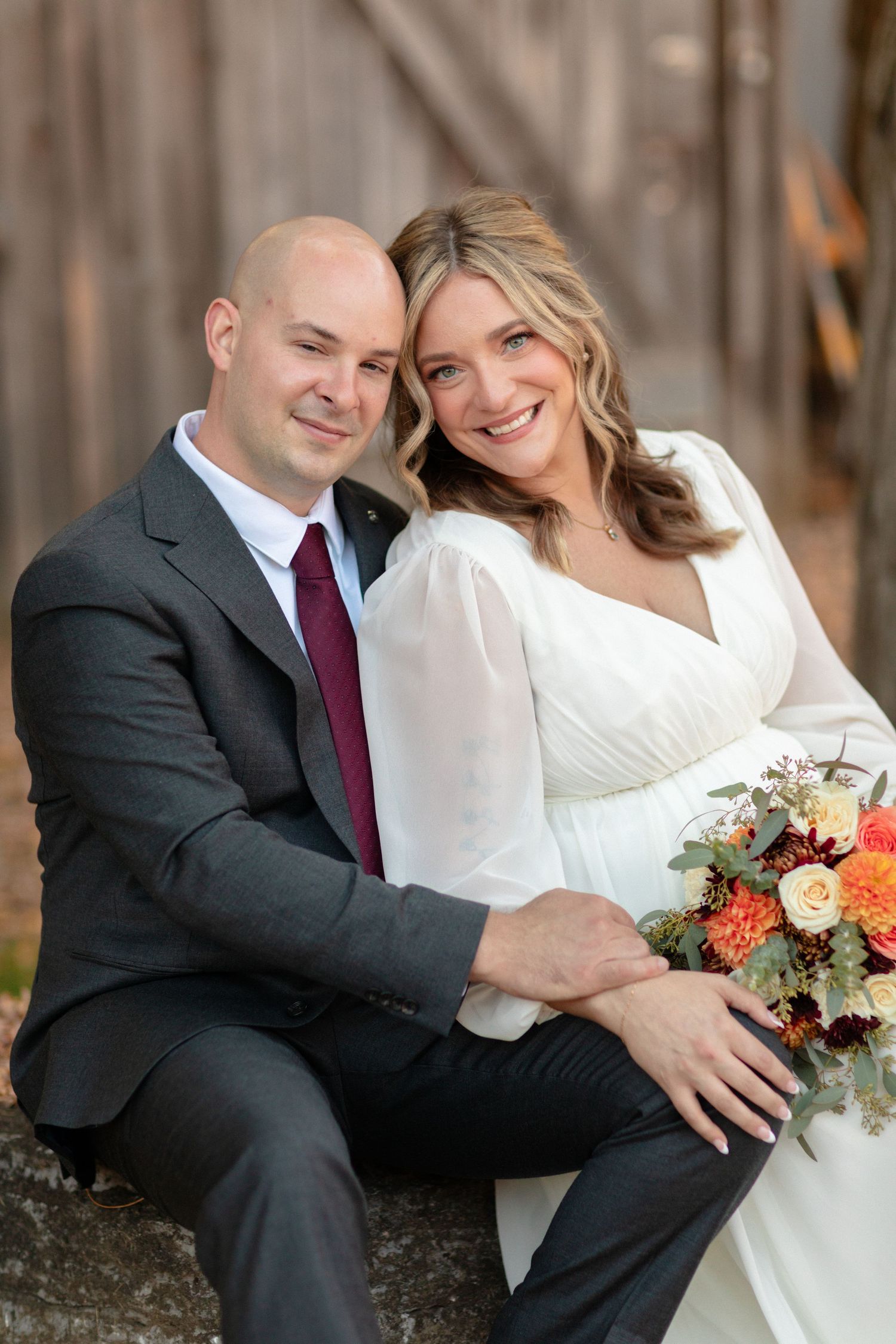 Candid wedding portraits of a couple sitting together with autumn floral bouquet.