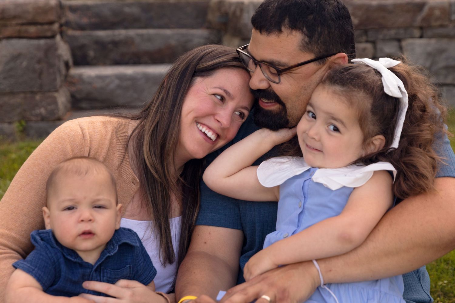 Family sitting together on stone steps during an outdoor photo session in casual clothing.