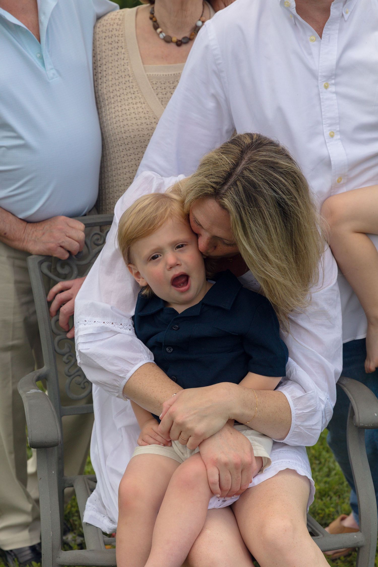 Candid family moment captured outdoors with casual white attire.