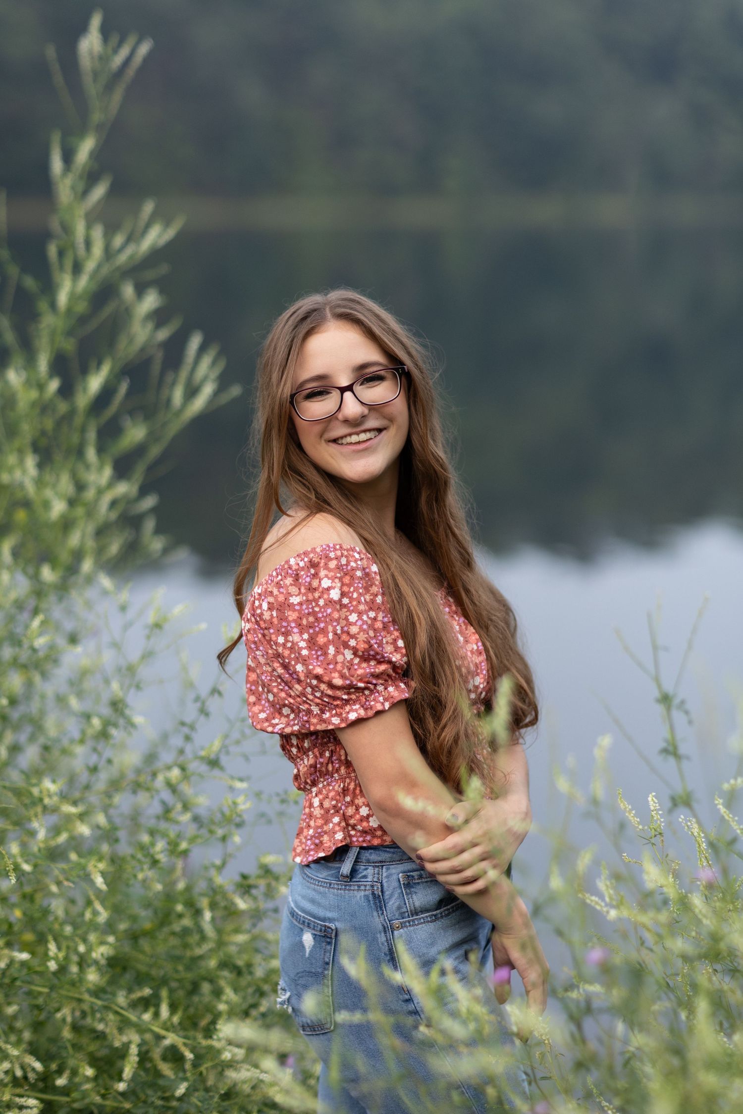 Nature-themed portraits by lake with wildflowers and natural scenery.