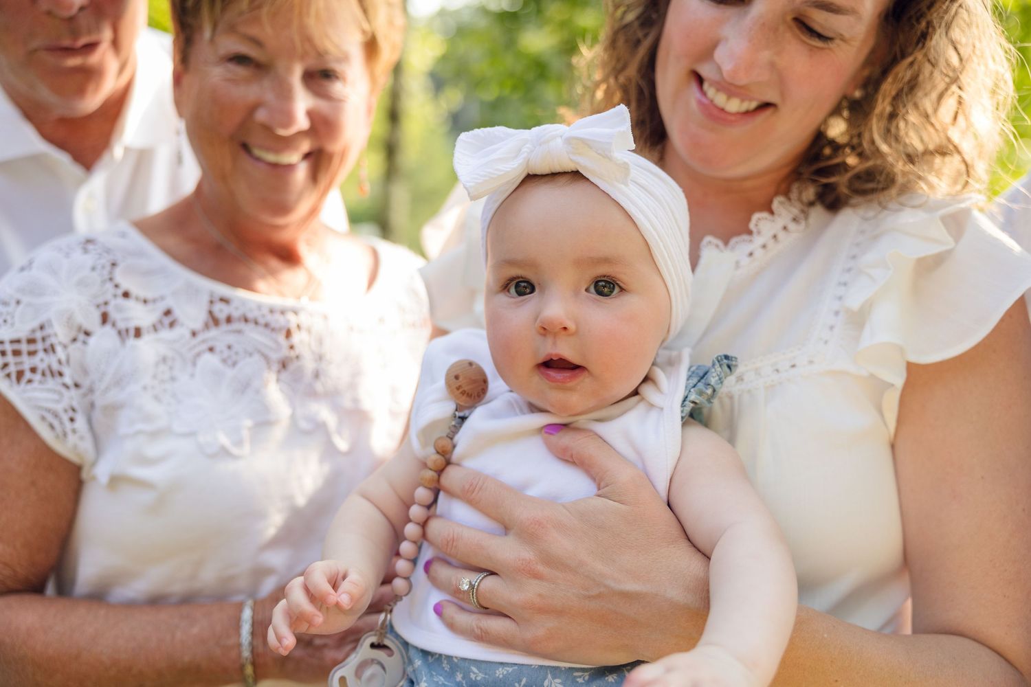Loving family portraits captured outdoors with everyone wearing coordinating white outfits.