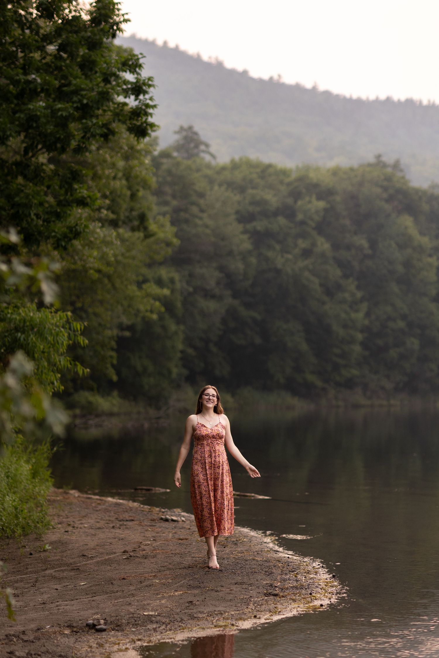 A floral dress silhouette walking along a peaceful lakeside shore.