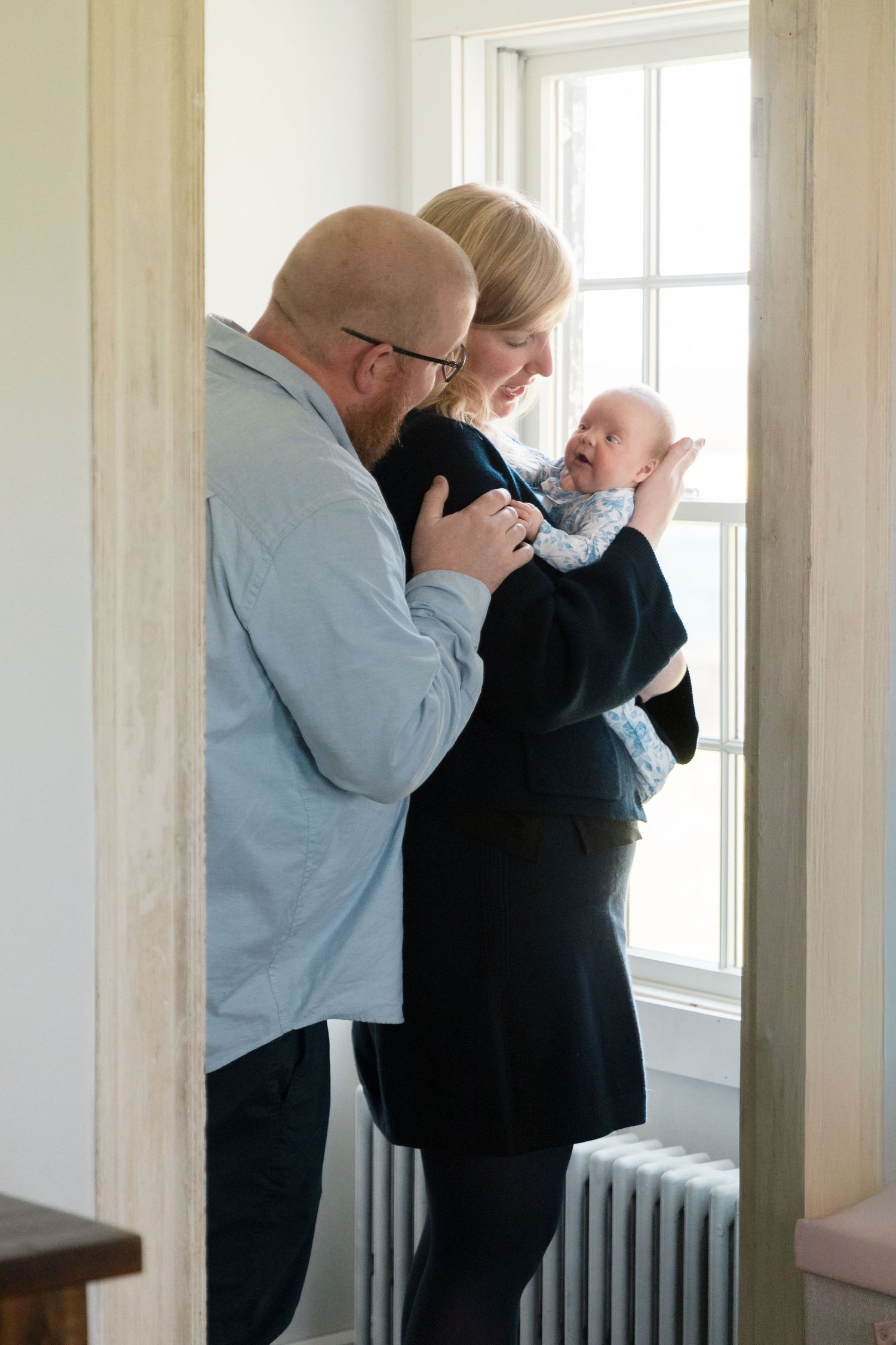 Intimate indoor photo sequence showing tender moments between parent and baby against bright window light.